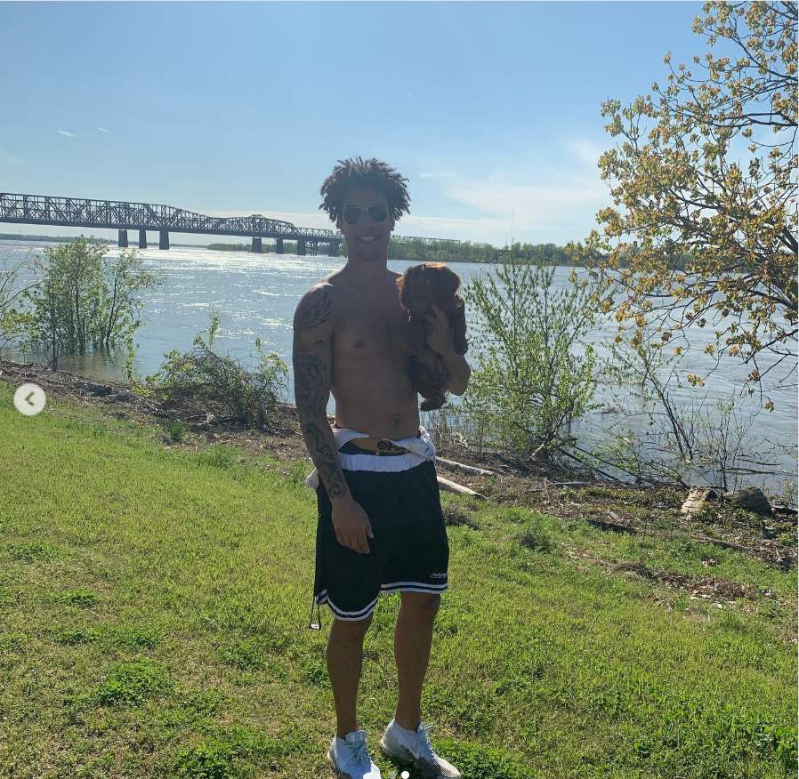 Brandon Clarke still holds his dog beside the water during an outdoor outing near a riverside bridge. | Source: Instagram/brandon_clarke23