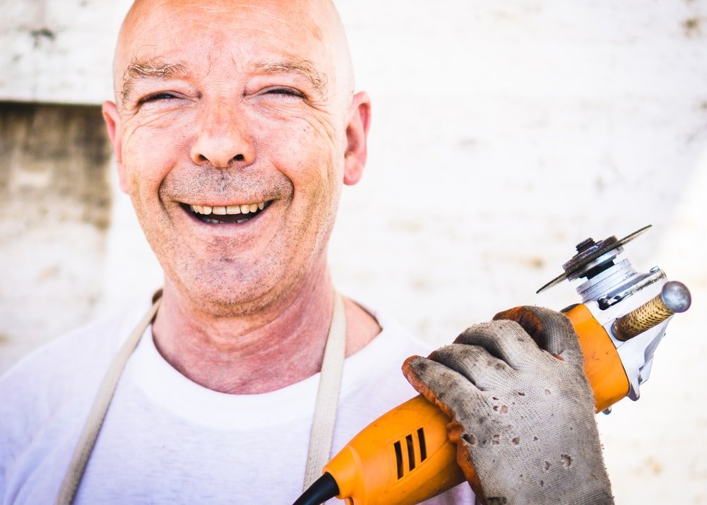 Trabajador sonriendo con una cortadora en la mano. | Foto: Unsplash