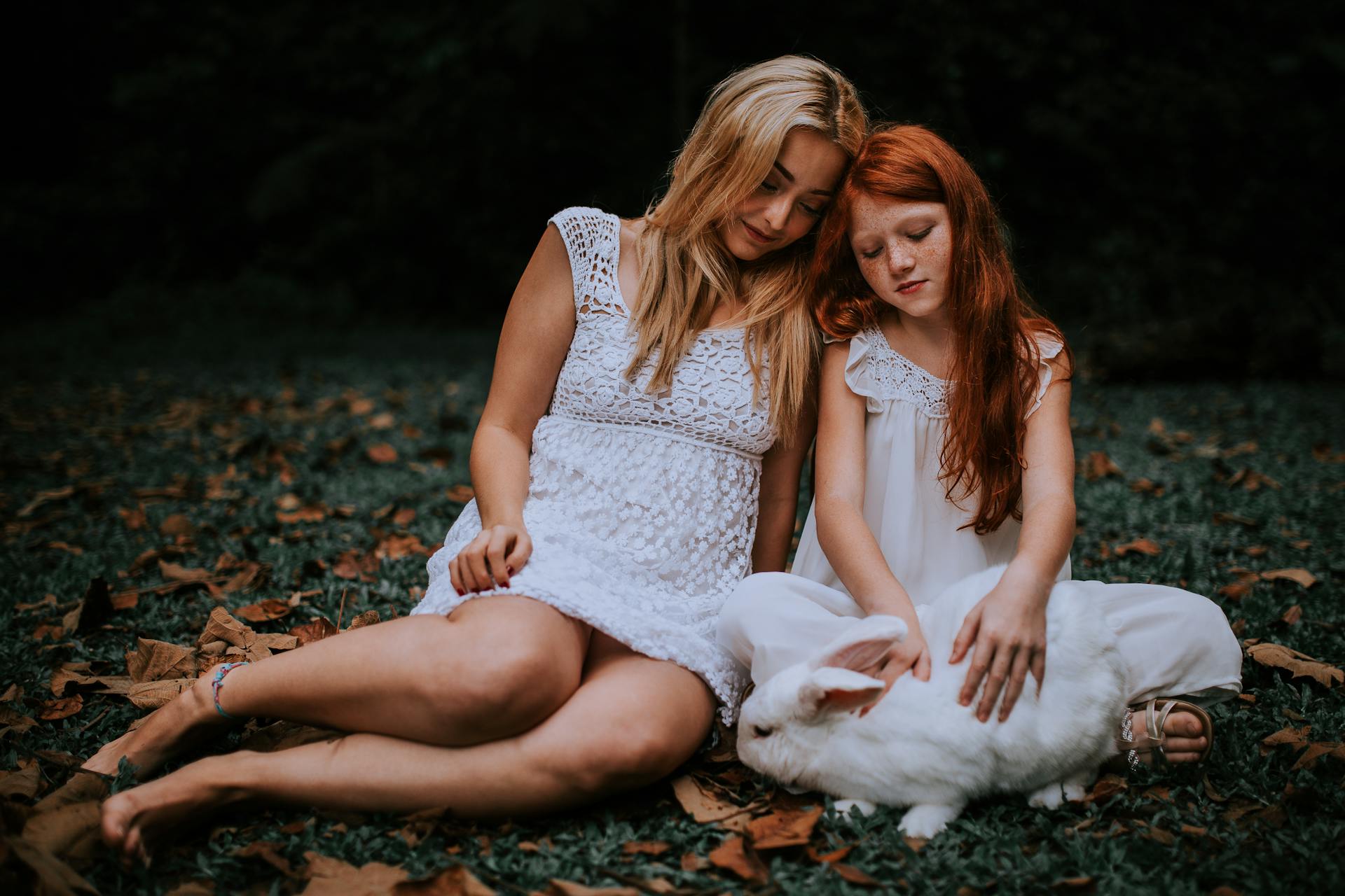 A woman sitting on the grass with a little girl | Source: Pexels