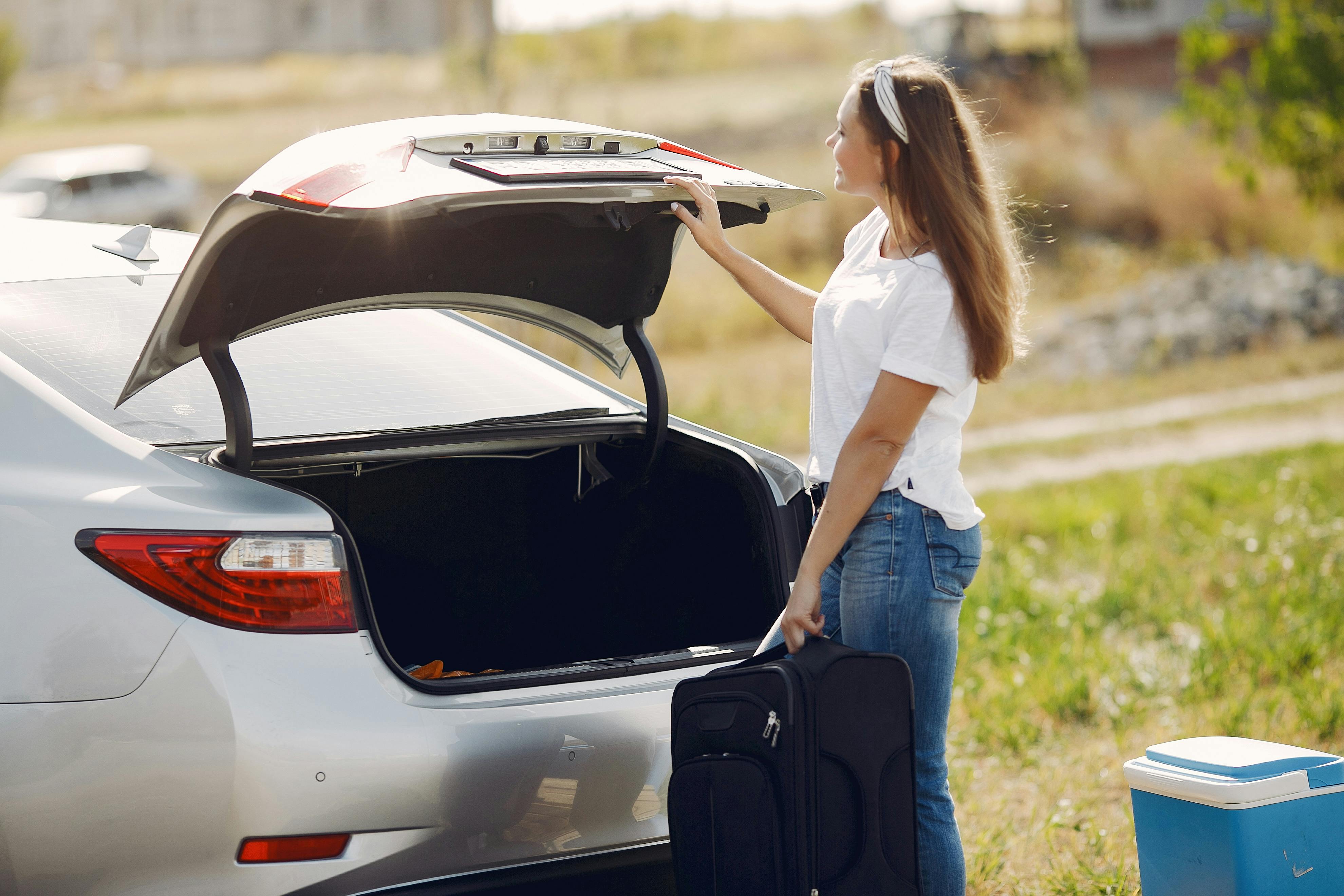 A woman standing near a car with her luggage | Source: Pexels