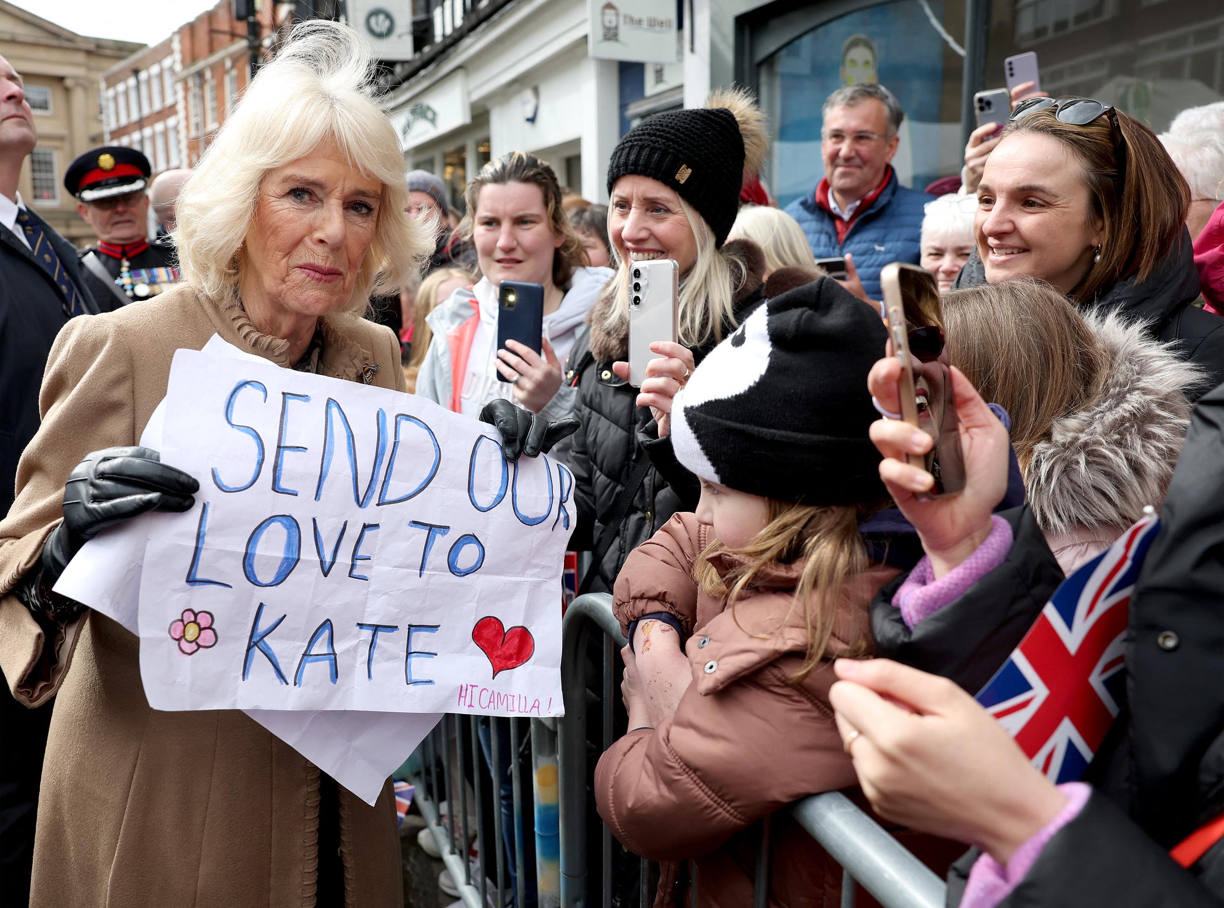 Queen Camilla holds a well-wishers' banner reading "Send our love to Kate" during her visit to the Farmers' Market in Shrewsbury, England on March 27, 2024. | Source: Getty Images