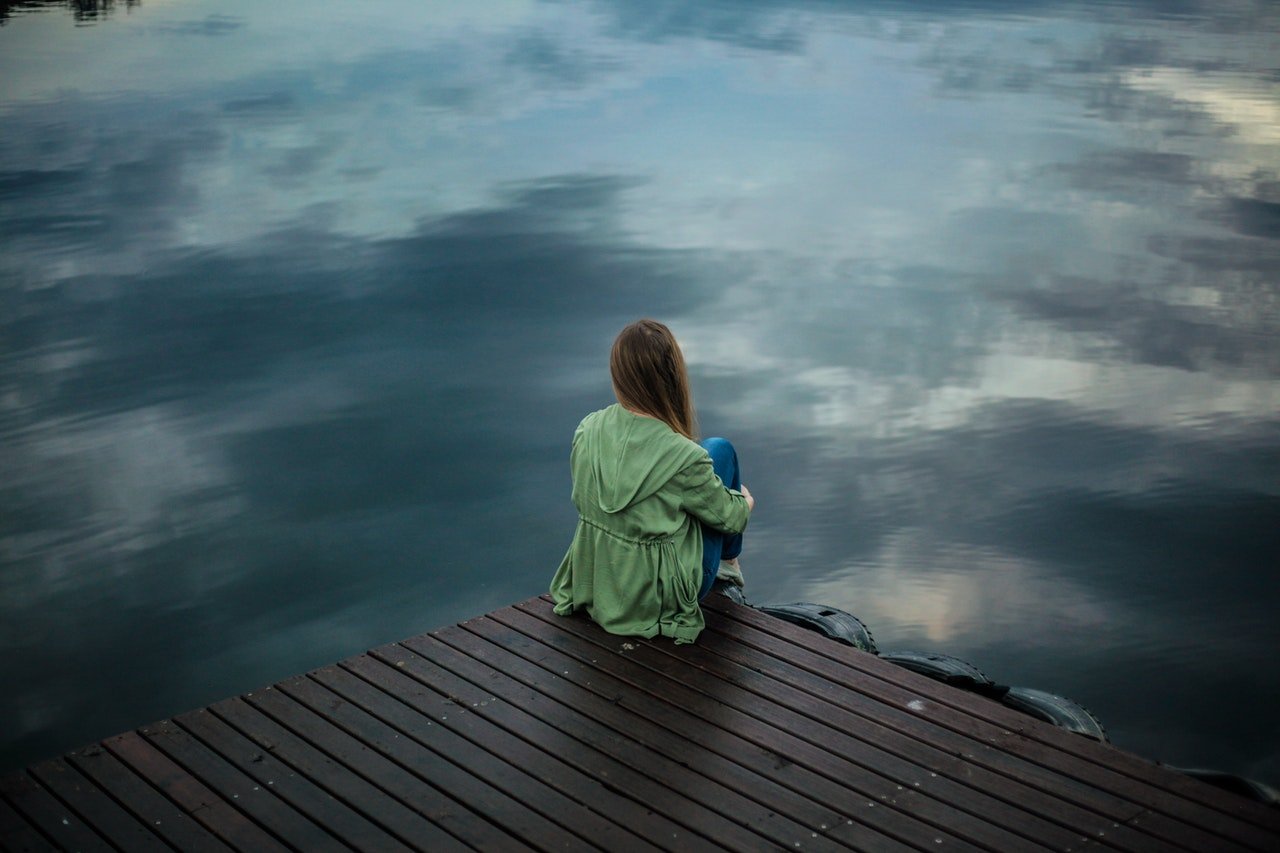 A woman thinking as she looks out over the water. | Source: Pexels.