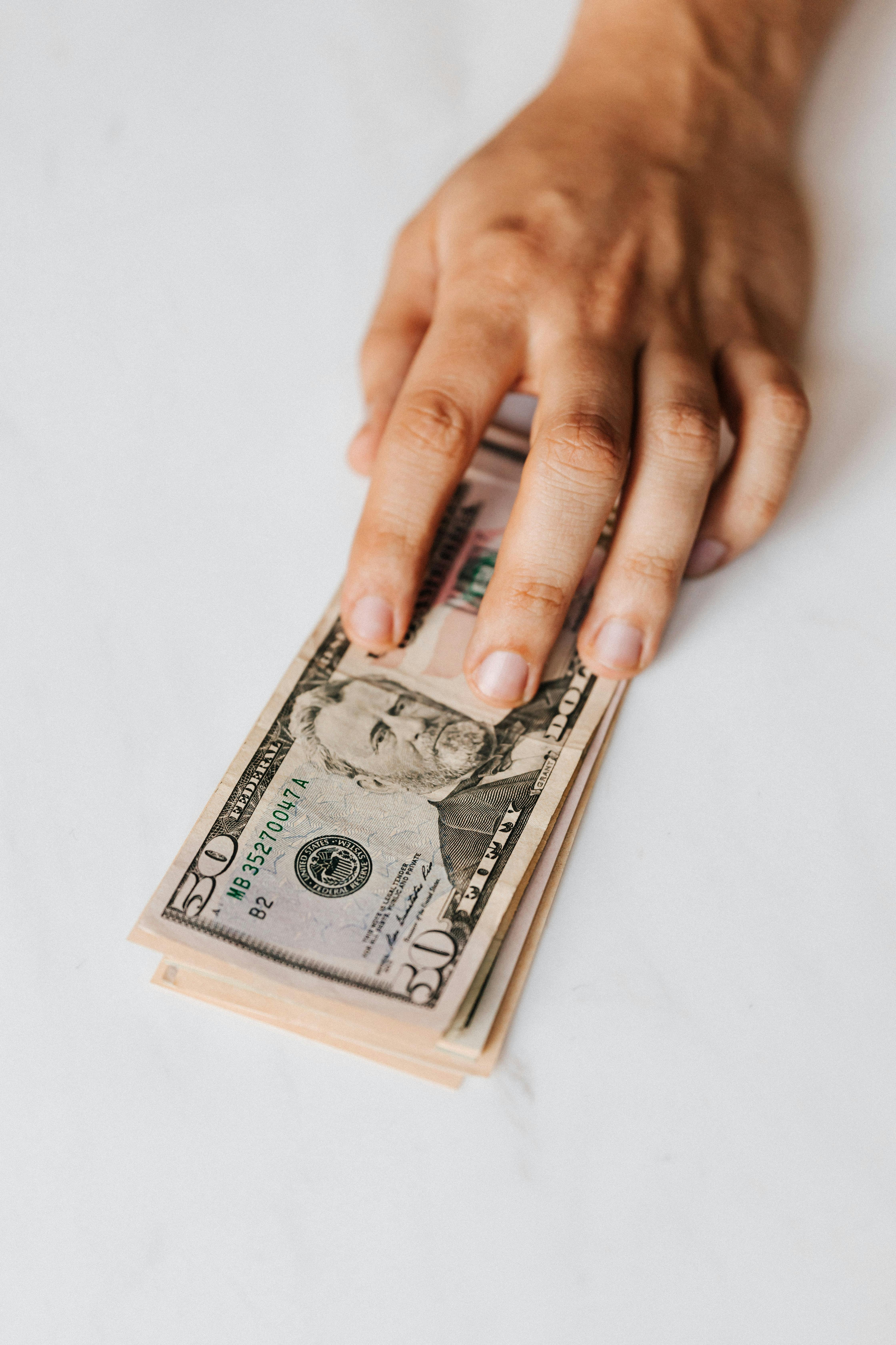 A person putting pile of paper money on table | Source: Pexels