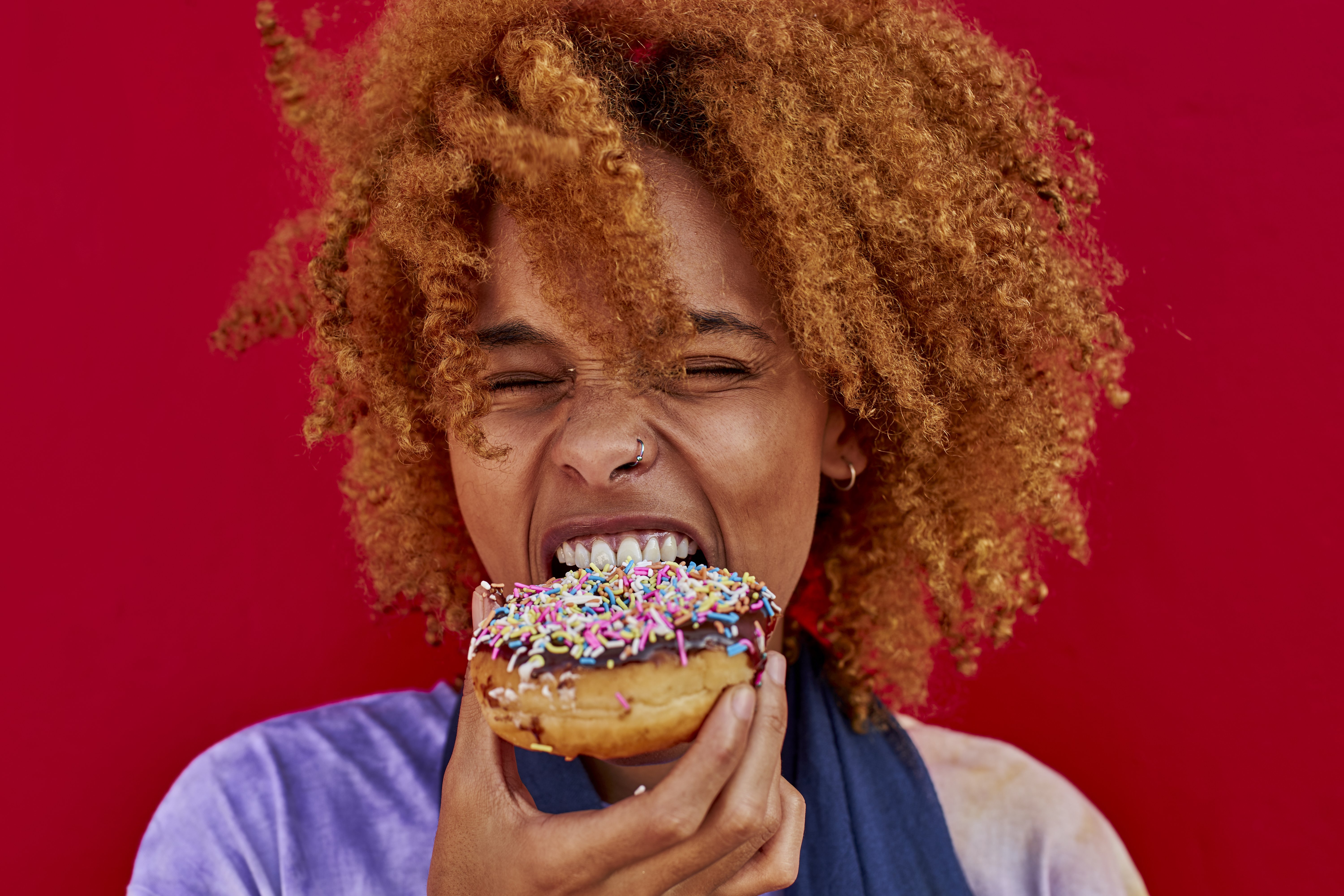 A portrait of woman eating a donut | Source: Getty Images