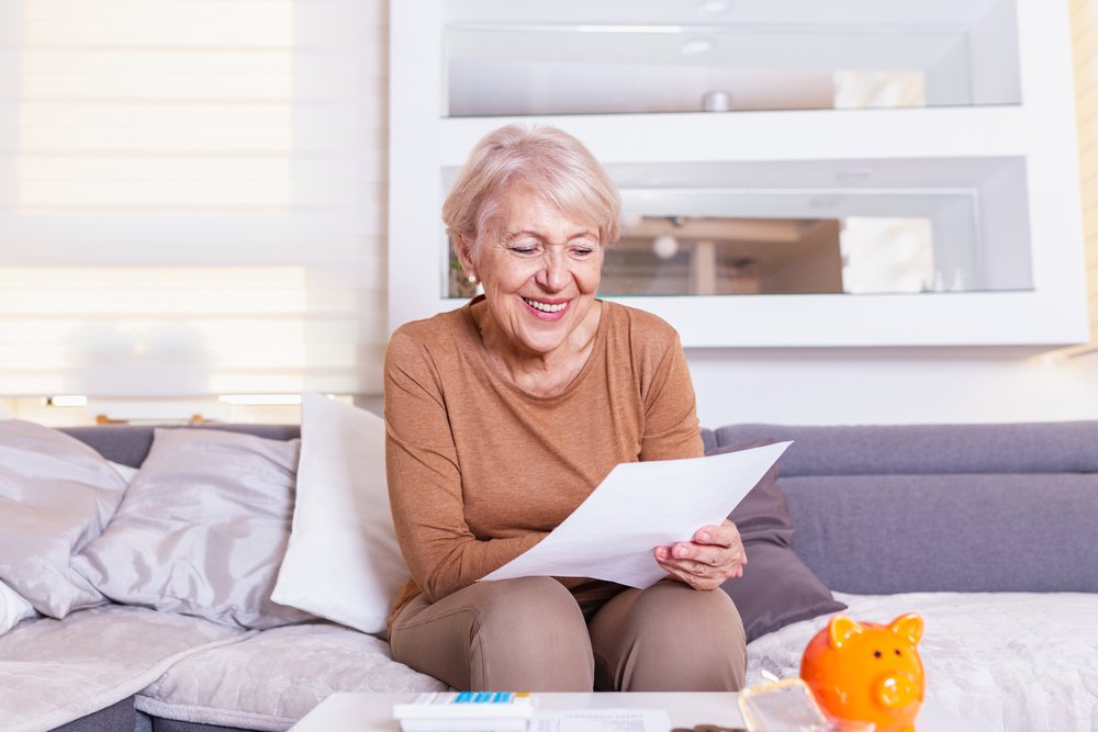 Ältere Frau, die über ihre Finanzen lächelt und glücklich ist. I Quelle: Shutterstock