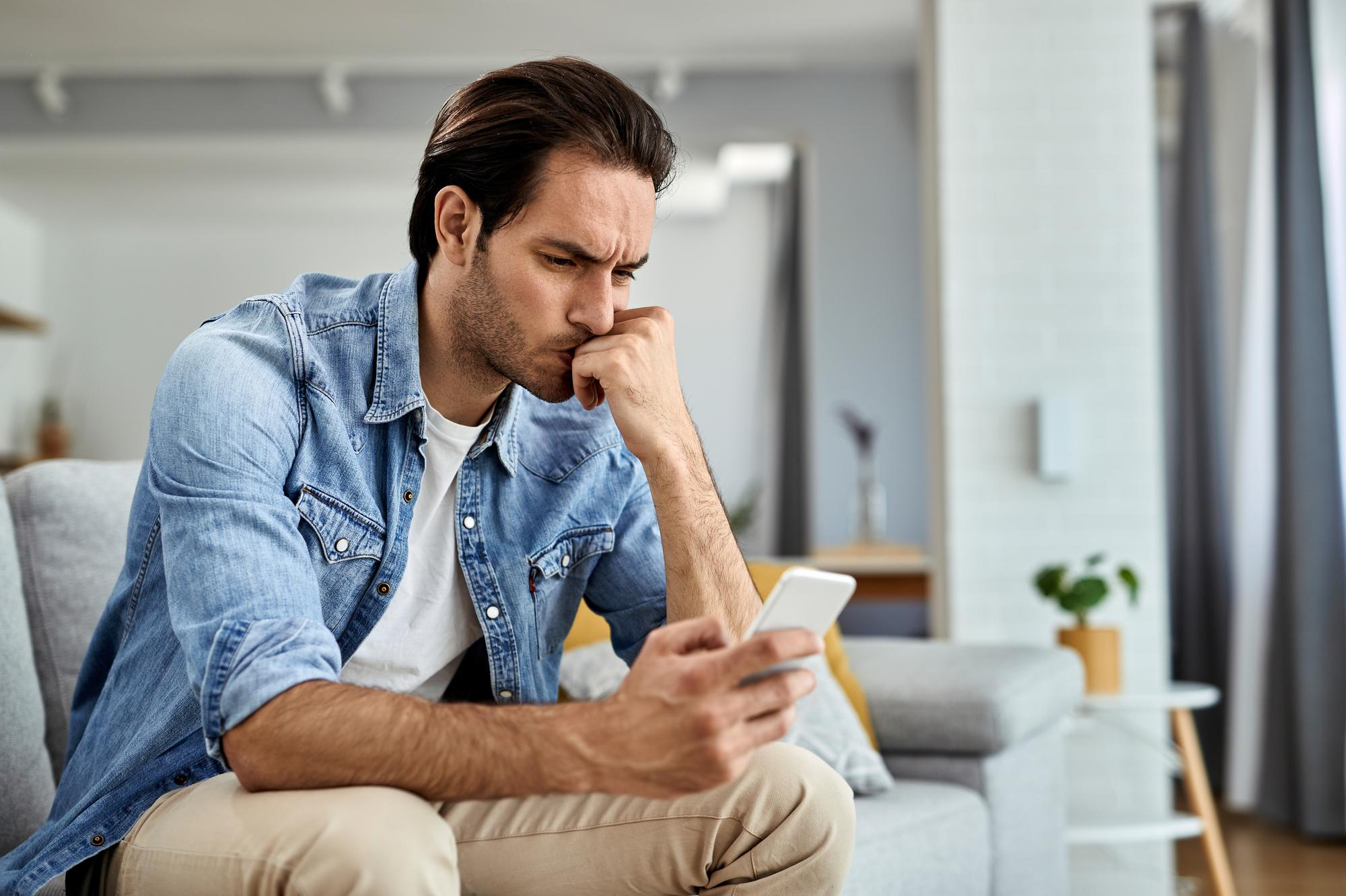 A man contemplating something while looking at his phone | Source: Freepik