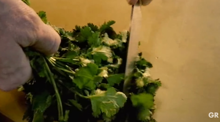 Gordon Ramsay shows how he prepares coriander by removing the leaves from the stalks before making one clean chop. He advises against repeatedly hacking at the herbs, noting that excessive chopping bruises them and diminishes their fresh flavor. | Source: YouTube/ Gordon Ramsay