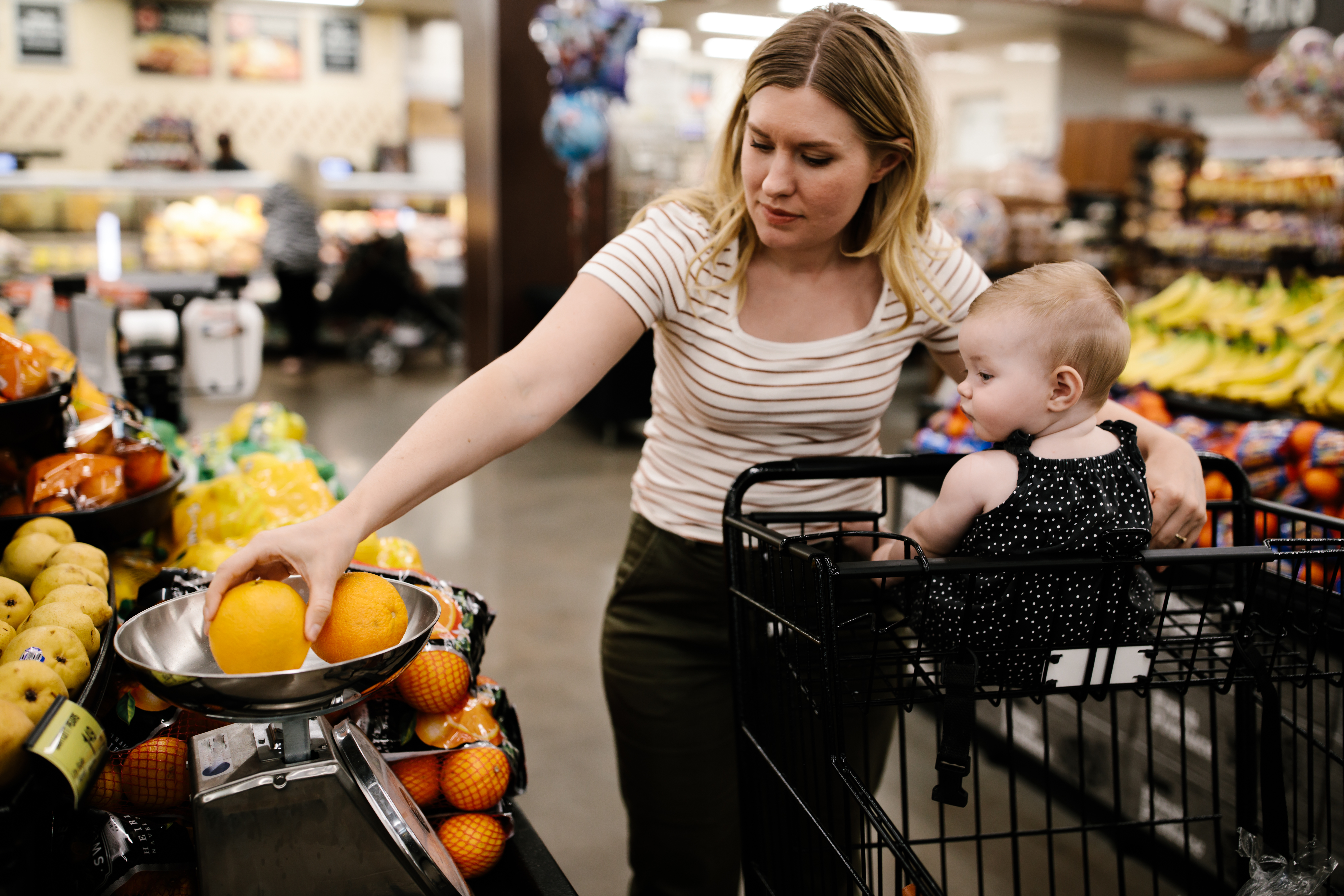 Mother with her little daughter buying fresh fruit at the grocery store | Source: Getty Images