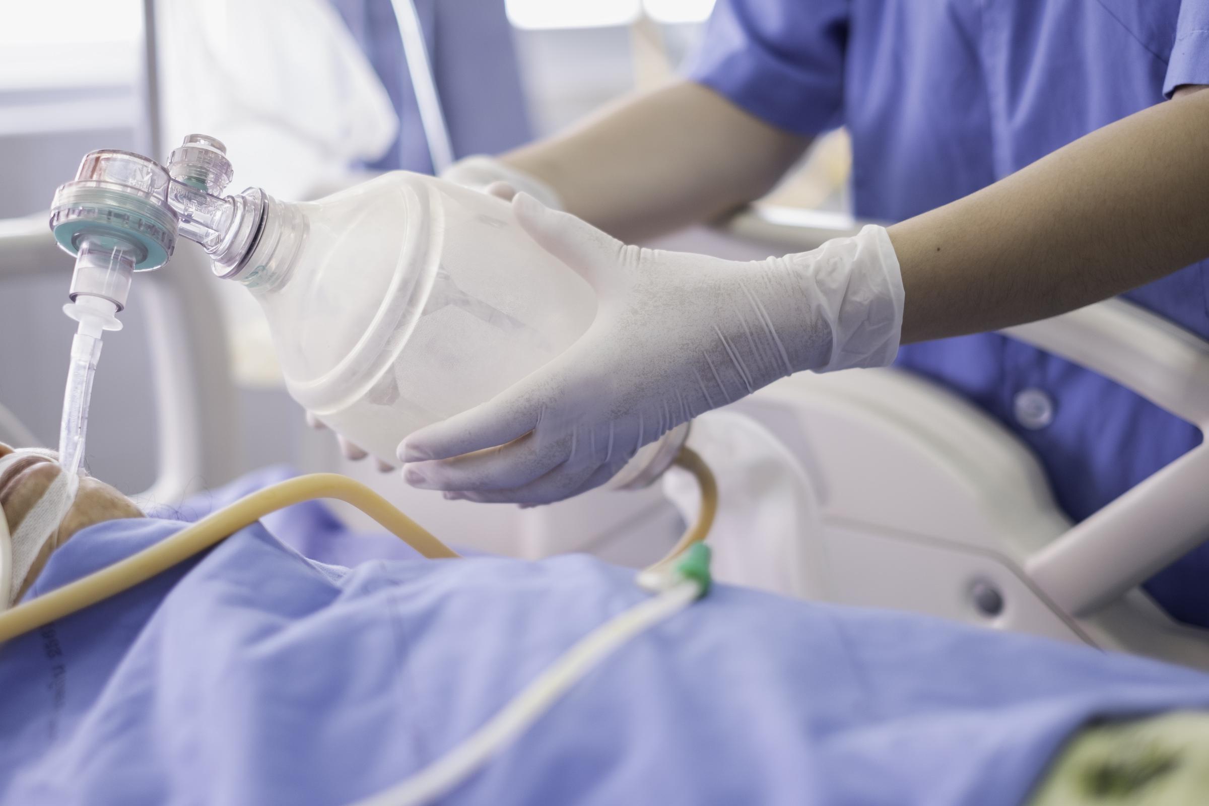 A doctor holding an oxygen ambu bag over a patient in the ICU/emergency room | Source: Getty Images