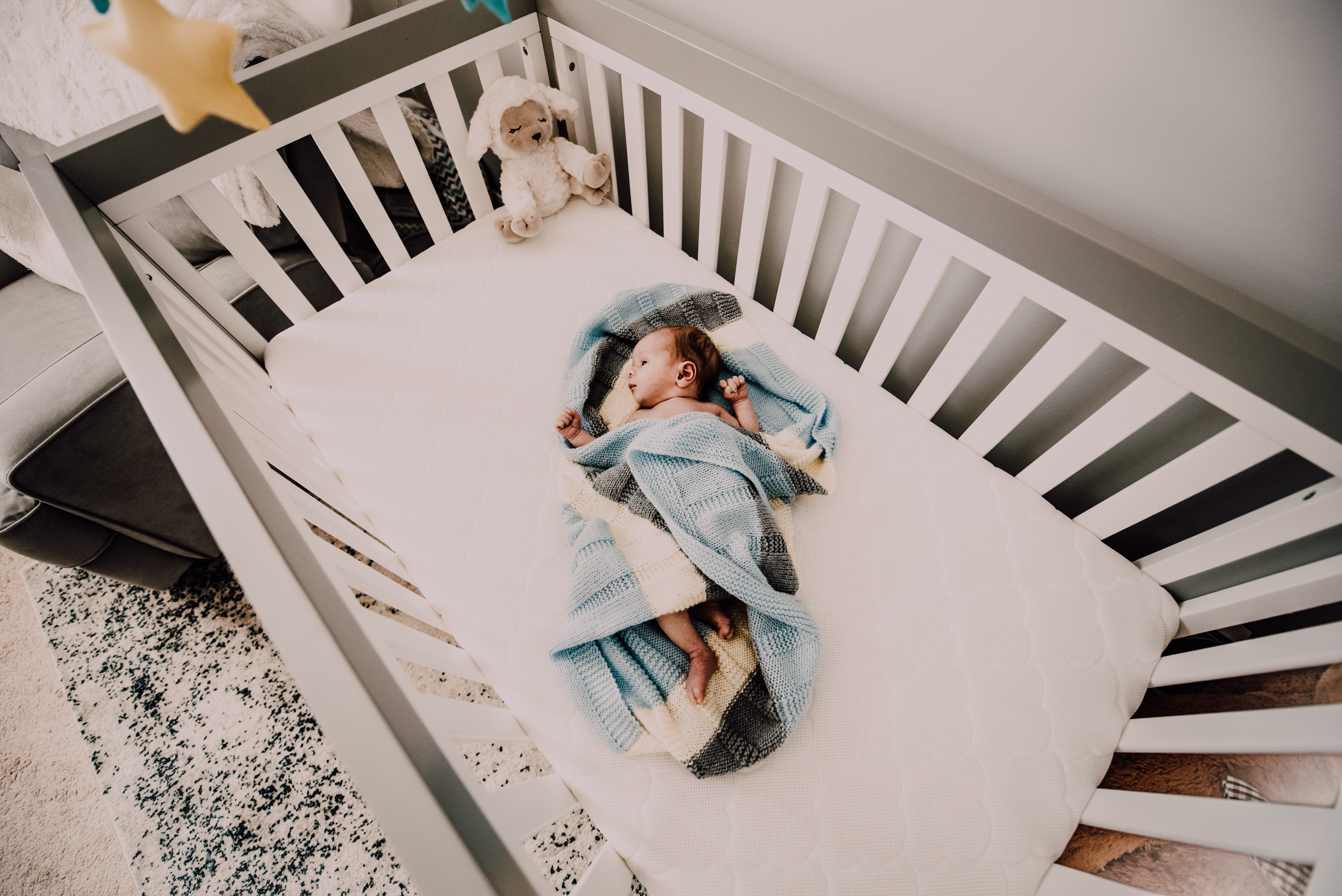 A baby wrapped in a blue blanket sleeping in a crib. | Photo: Pexels/Alicia