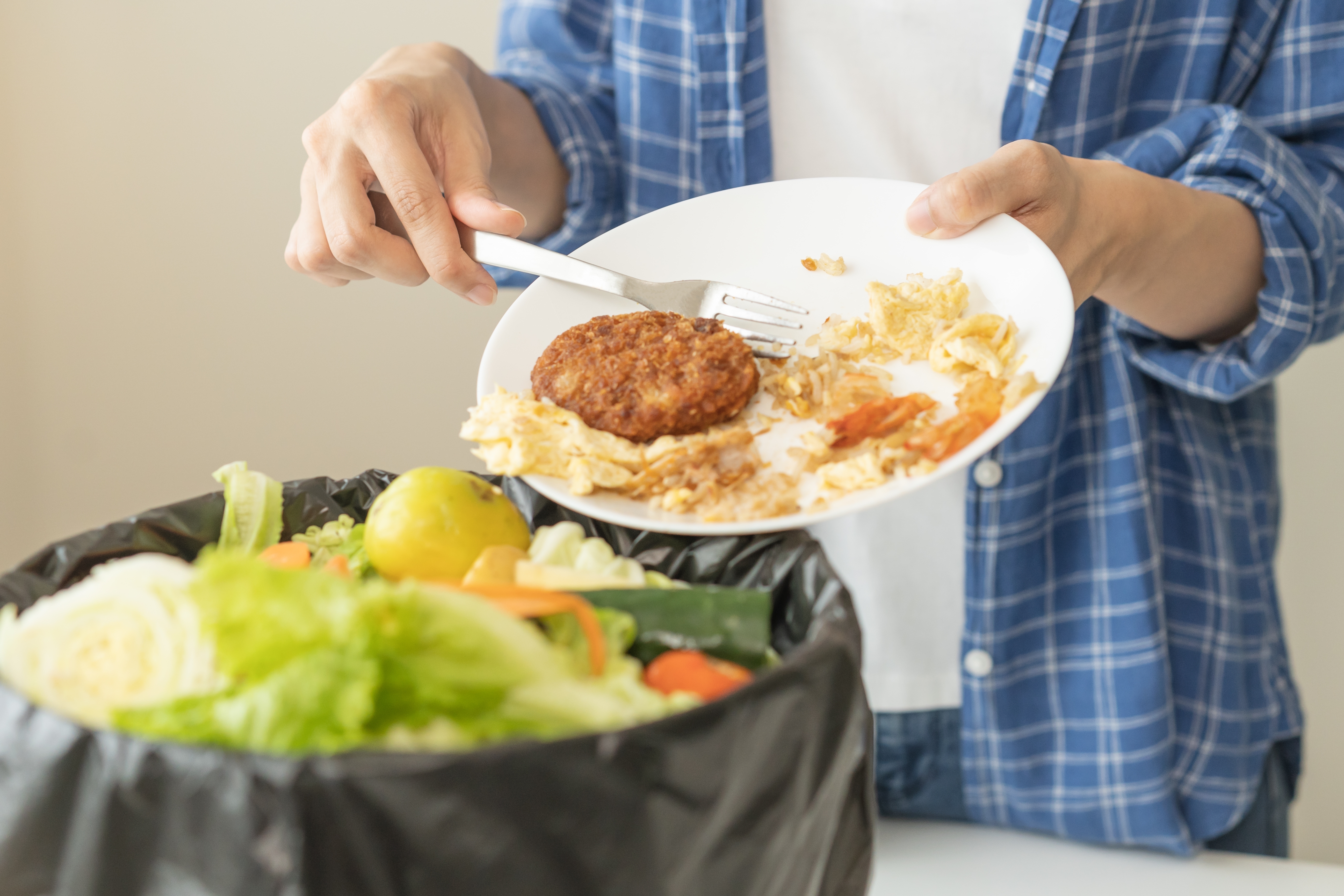 A person discarding food from a plate. | Source: Shutterstock