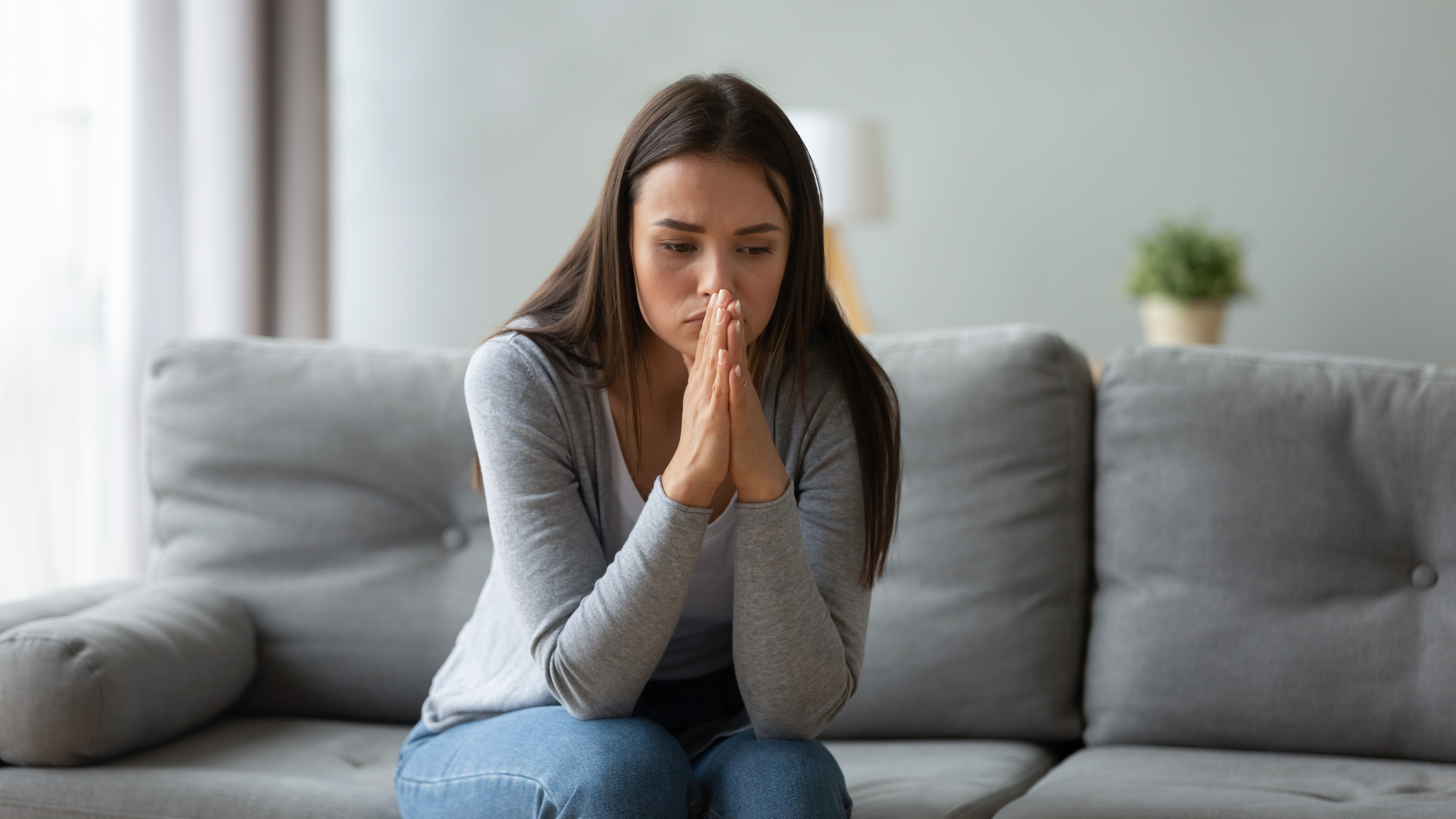 A distraught woman sitting on the sofa contemplating her future | Source: Shutterstock