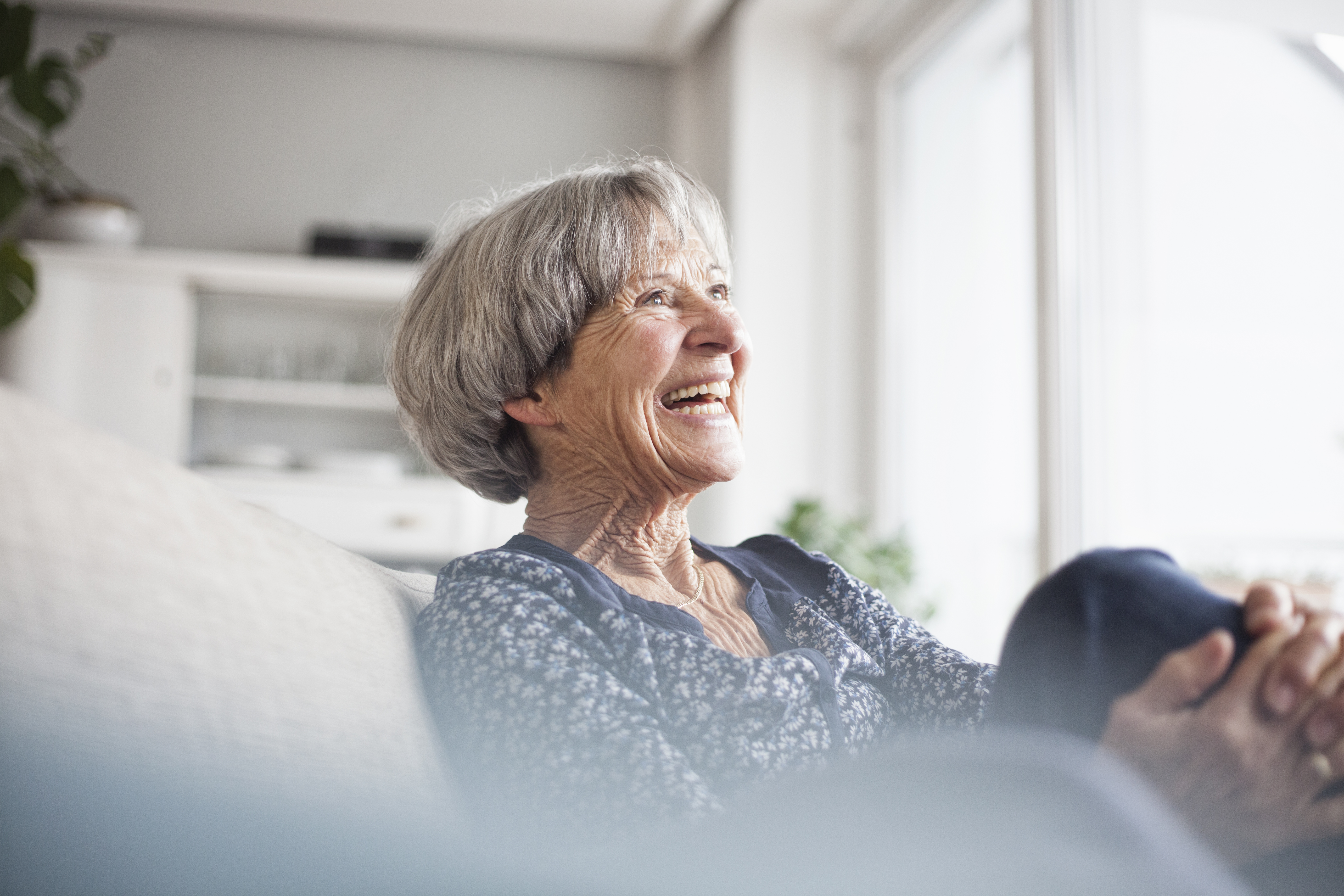 Portrait of laughing senior woman sitting on couch at home | Source: Getty Images