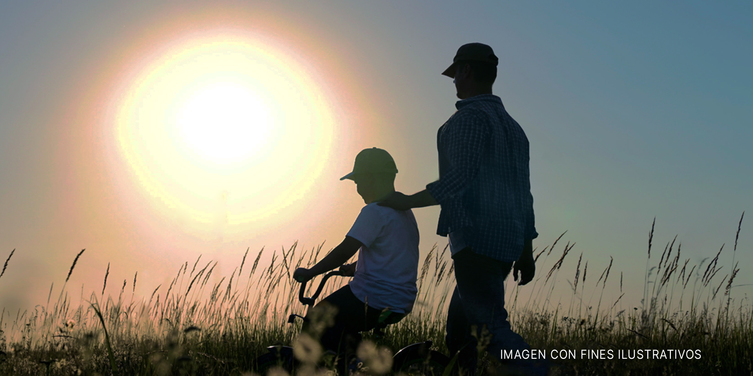 Niño en bicicleta junto a su padre en un campo. | Foto: Shutterstock