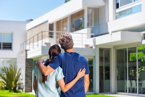 A couple embracing outside a big new house. | Source: Shutterstock.