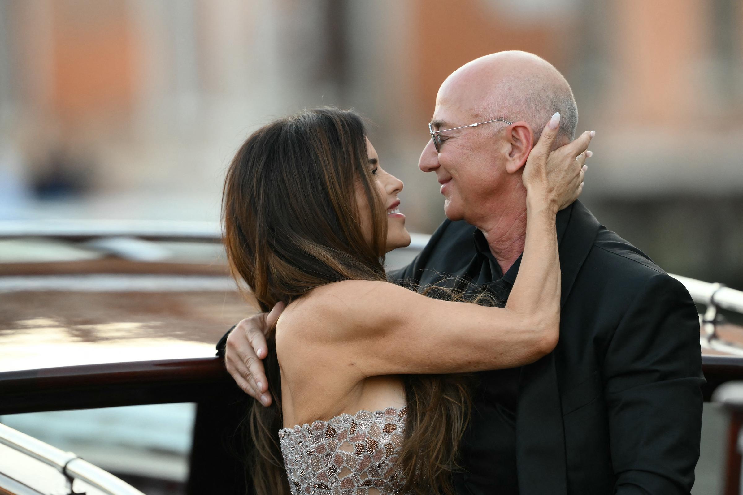 Lauren Sánchez gazes lovingly at Jeff Bezos, her hand resting gently on the side of his head as they share an intimate moment aboard the boat, their faces close and smiles soft.