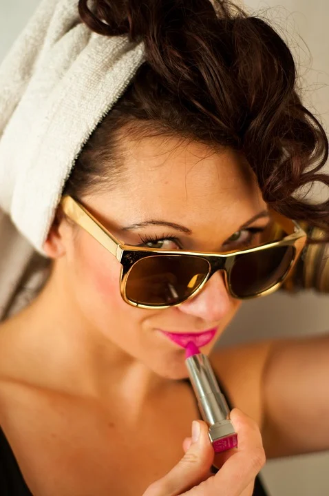 Mujer con lentes oscuros aplicándose lápiz labial. | Foto: Pixabay