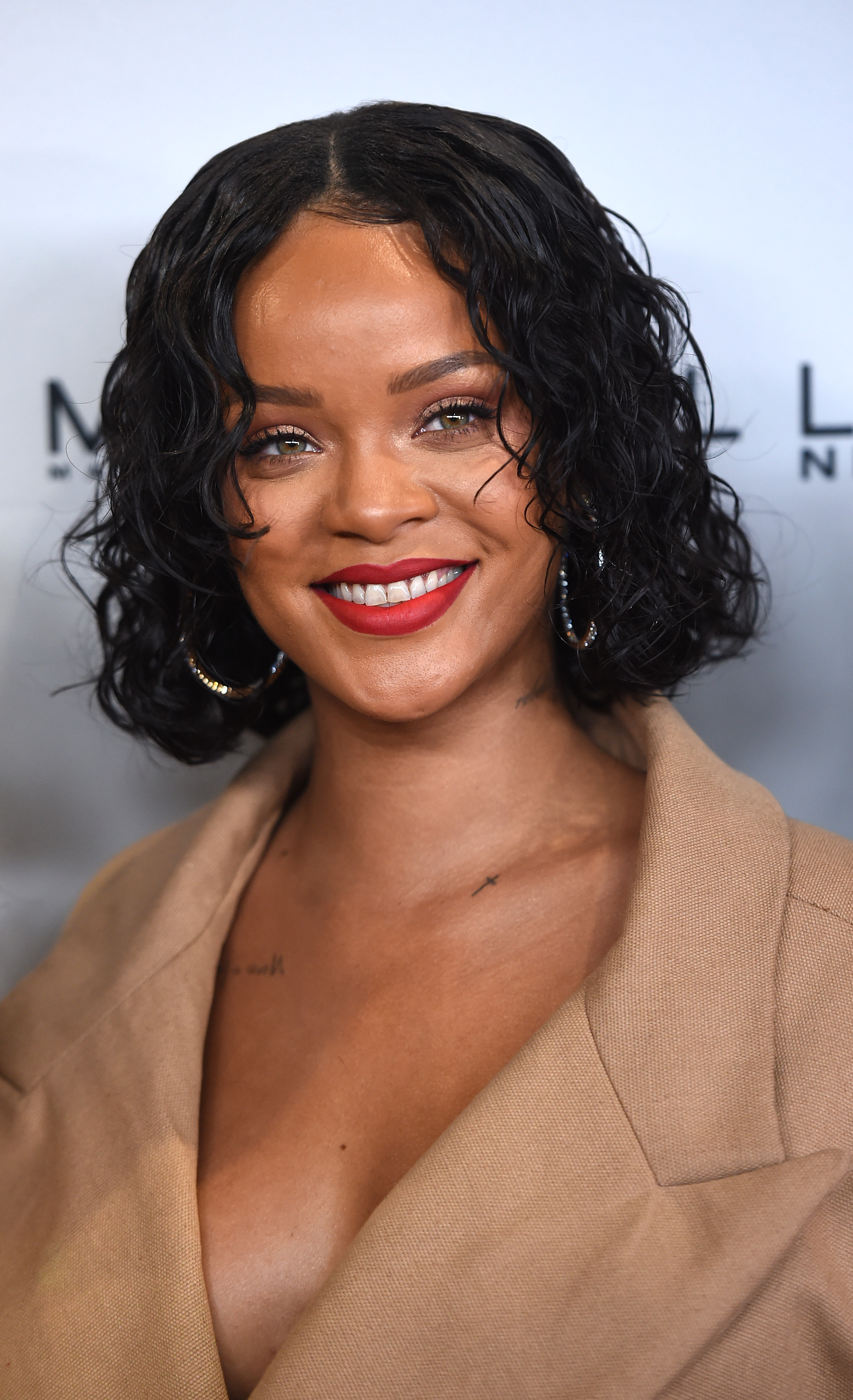 Rihanna brings warm, effortless elegance to the 69th Annual Parsons Benefit at Pier 60, while her textured curled hair and bold red lip radiate confidence. Wrapped in a chic neutral ensemble, she delivers her signature blend of grace and star power.