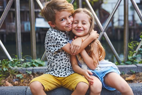 Niño abrazando a su hermana mientras sonríen a la cámara. | Foto: Shutterstock