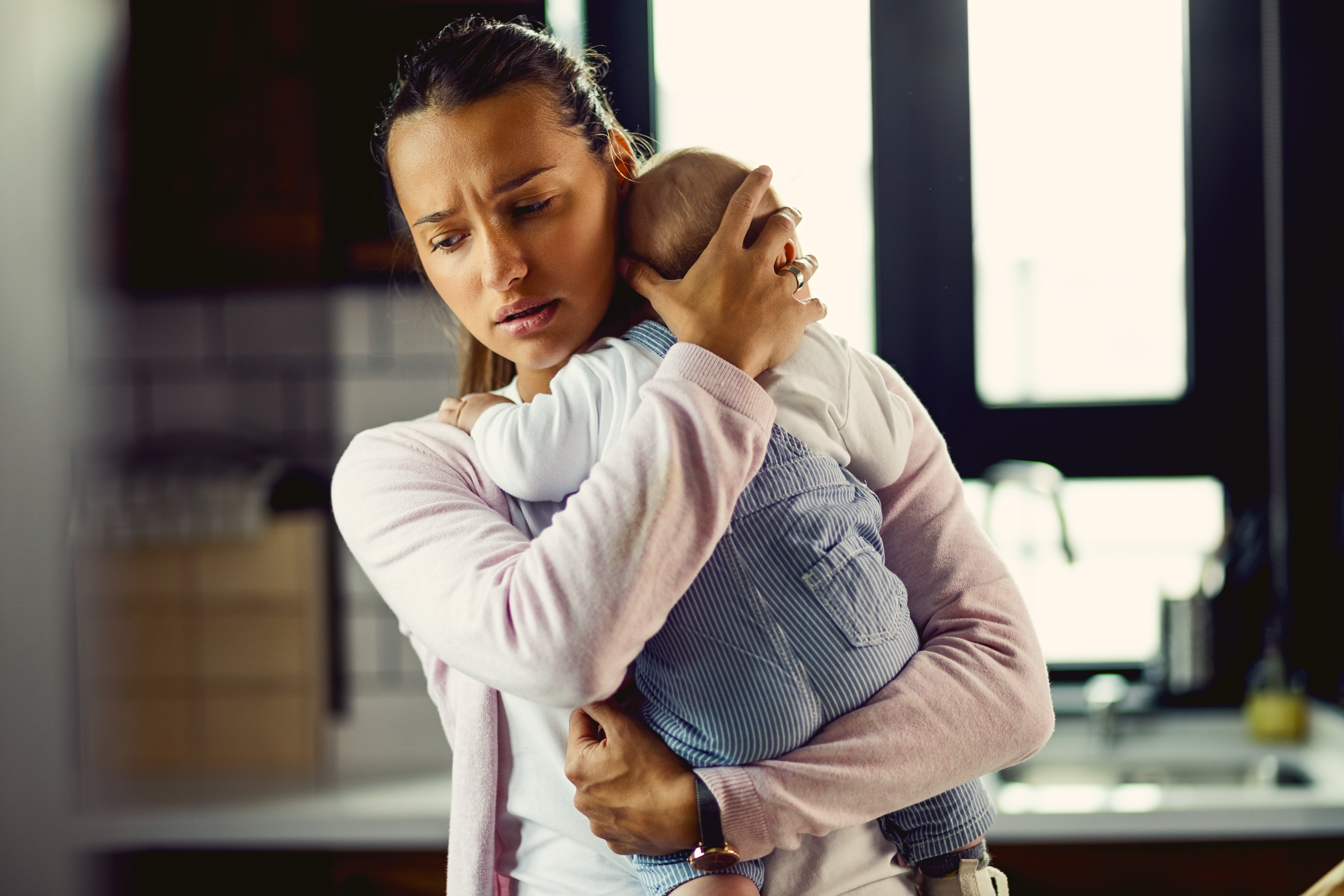 A worried young mom holding her baby | Source: Getty Images