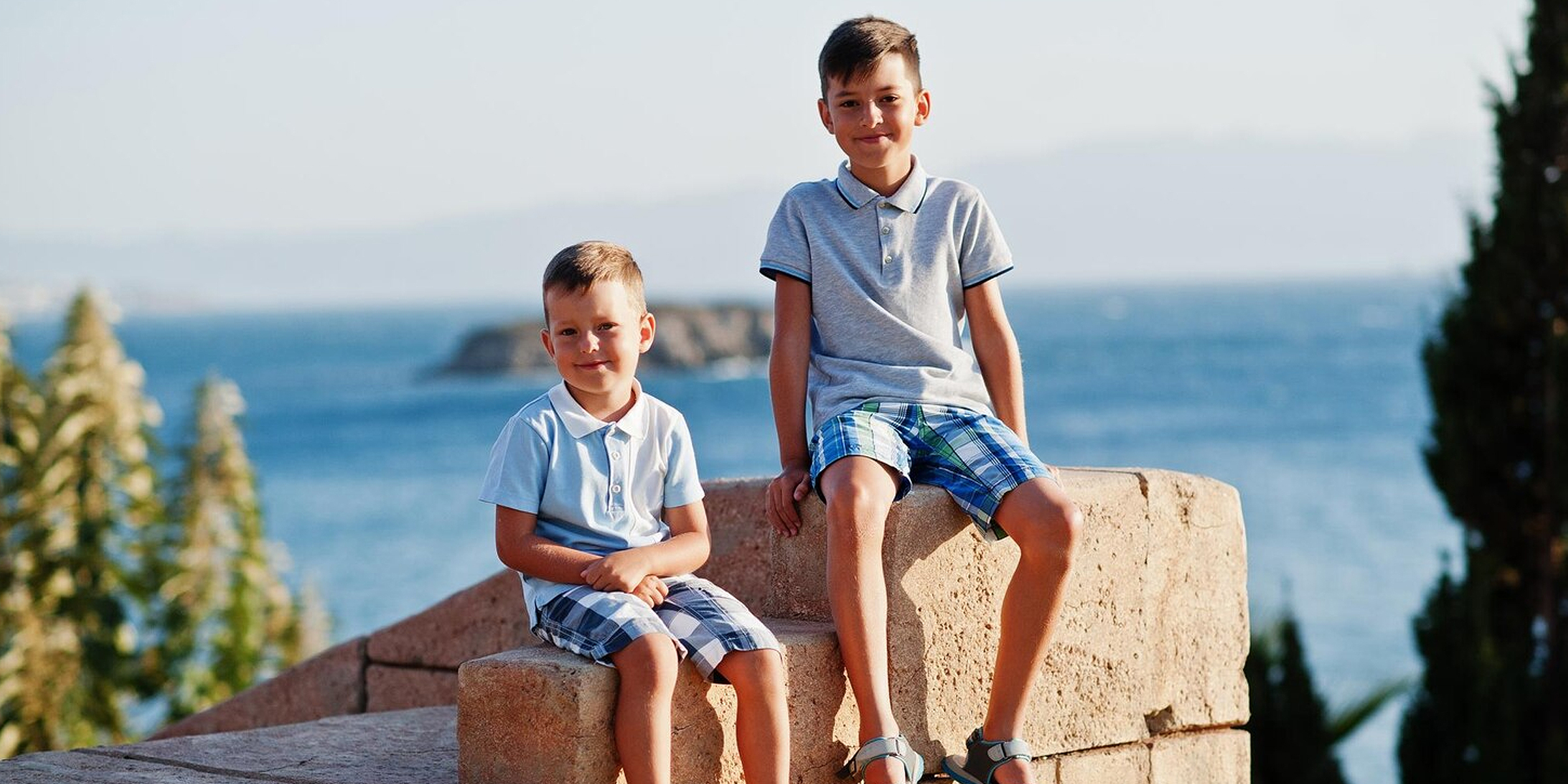 Two boys sitting outdoors | Source: Freepik