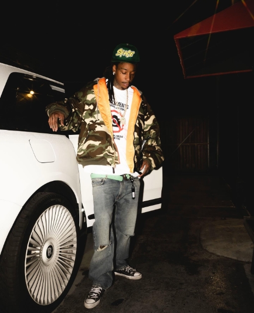 Wiz Khalifa wears a camouflage jacket, distressed denim, and a Chrome Hearts cap in a post dated March 12, 2025. | Source: Facebook/Wiz Khalifa