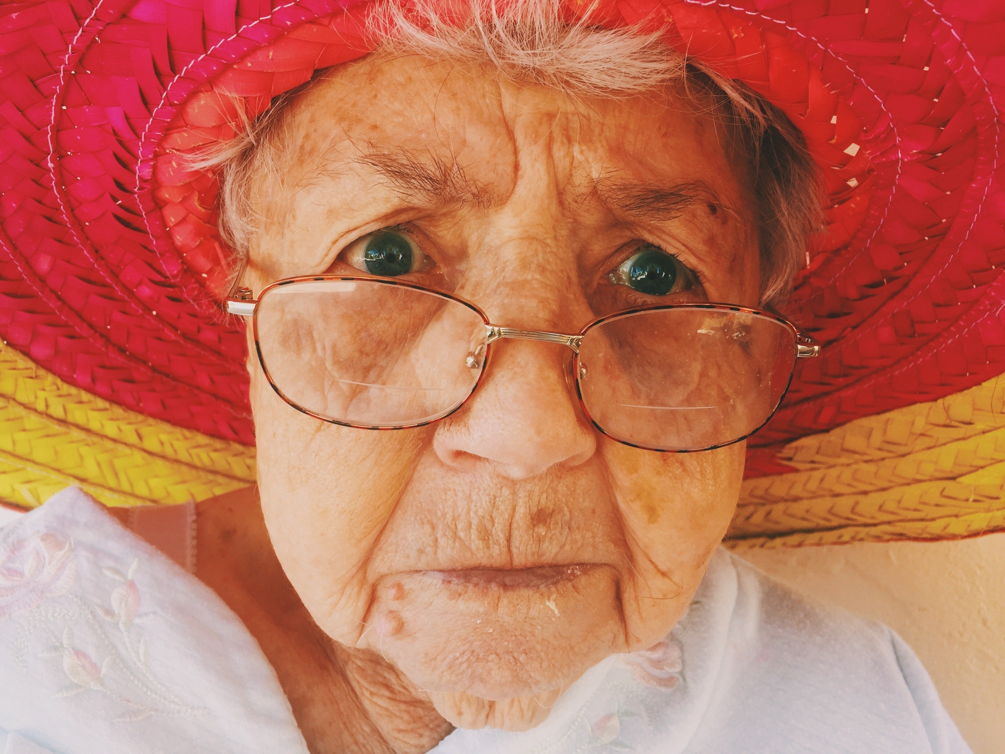 Una anciana con el rostro enojado usando un sombrero rojo y amarillo. | Foto: Pexels