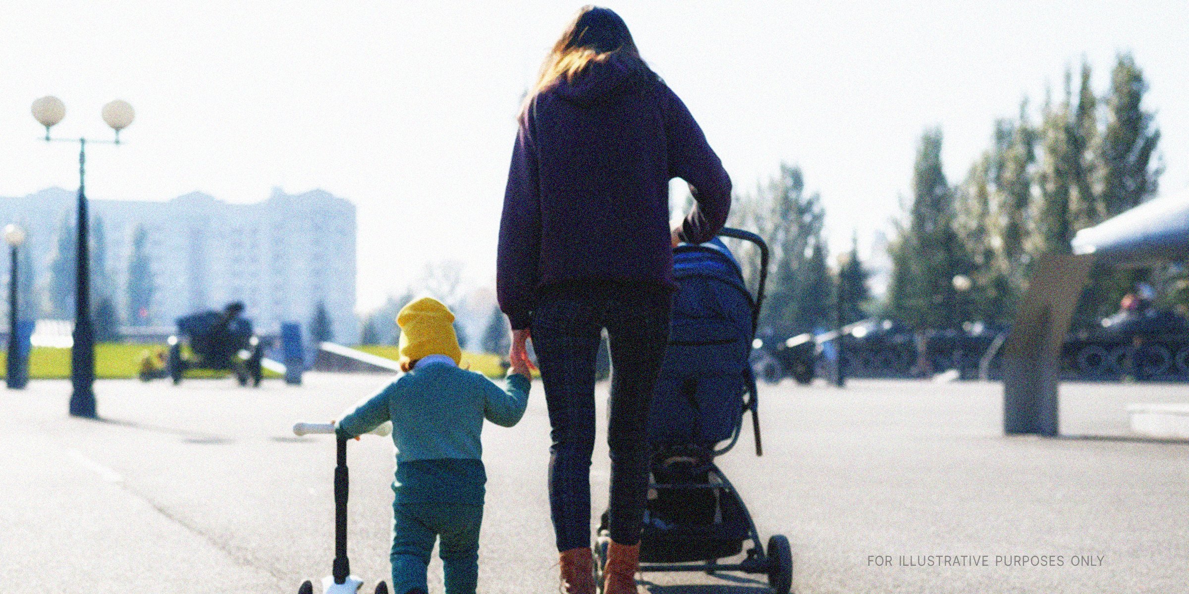 Woman walking her kid and pushing a stroller. | Shutterstock
