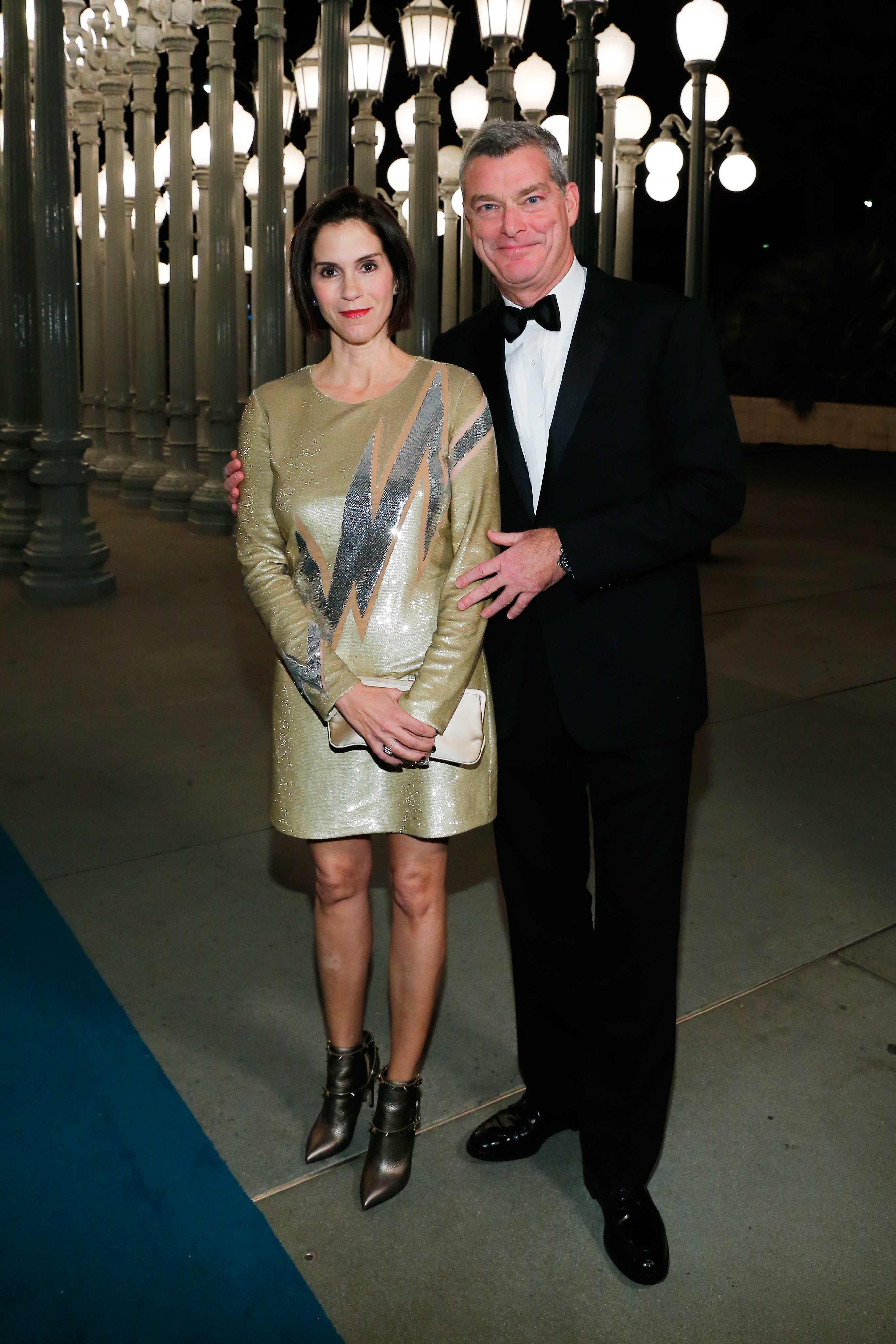 In a shimmering gold dress with bold lightning-bolt accents, Jami Gertz posed elegantly beside Tony Ressler at LACMA’s Art+Film Gala in Los Angeles.