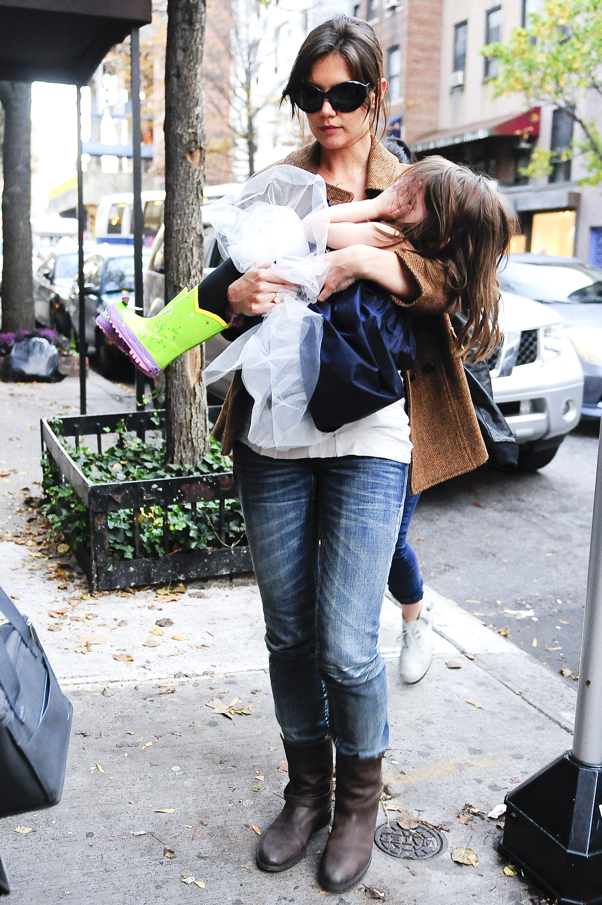 Katie Holmes carries Suri Cruise, who is covering her face, as they walk through Greenwich Village on November 22, 2009 | Source: Getty Images