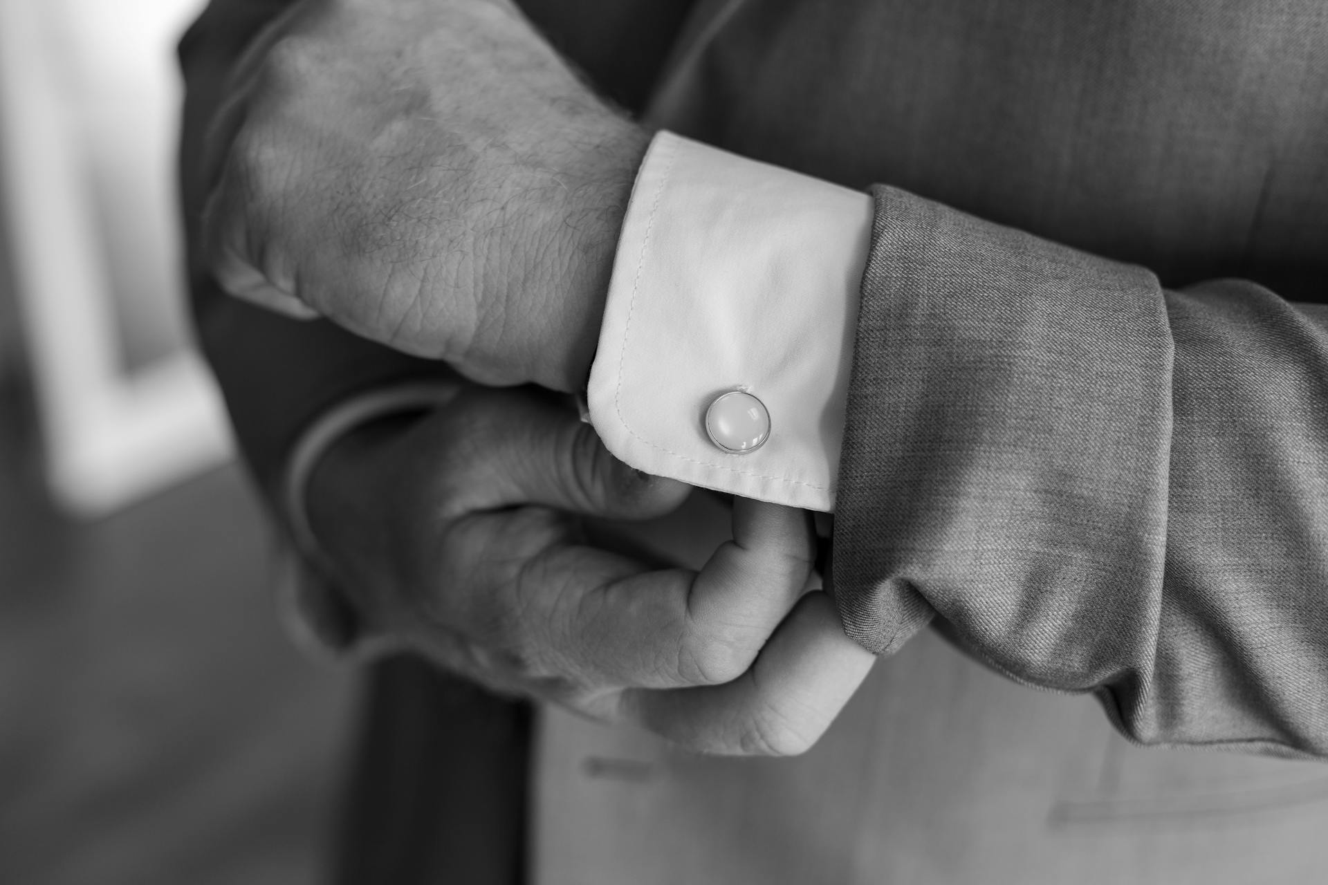 Grayscale photo of a man adjusting his cufflink | Source: Pexels
