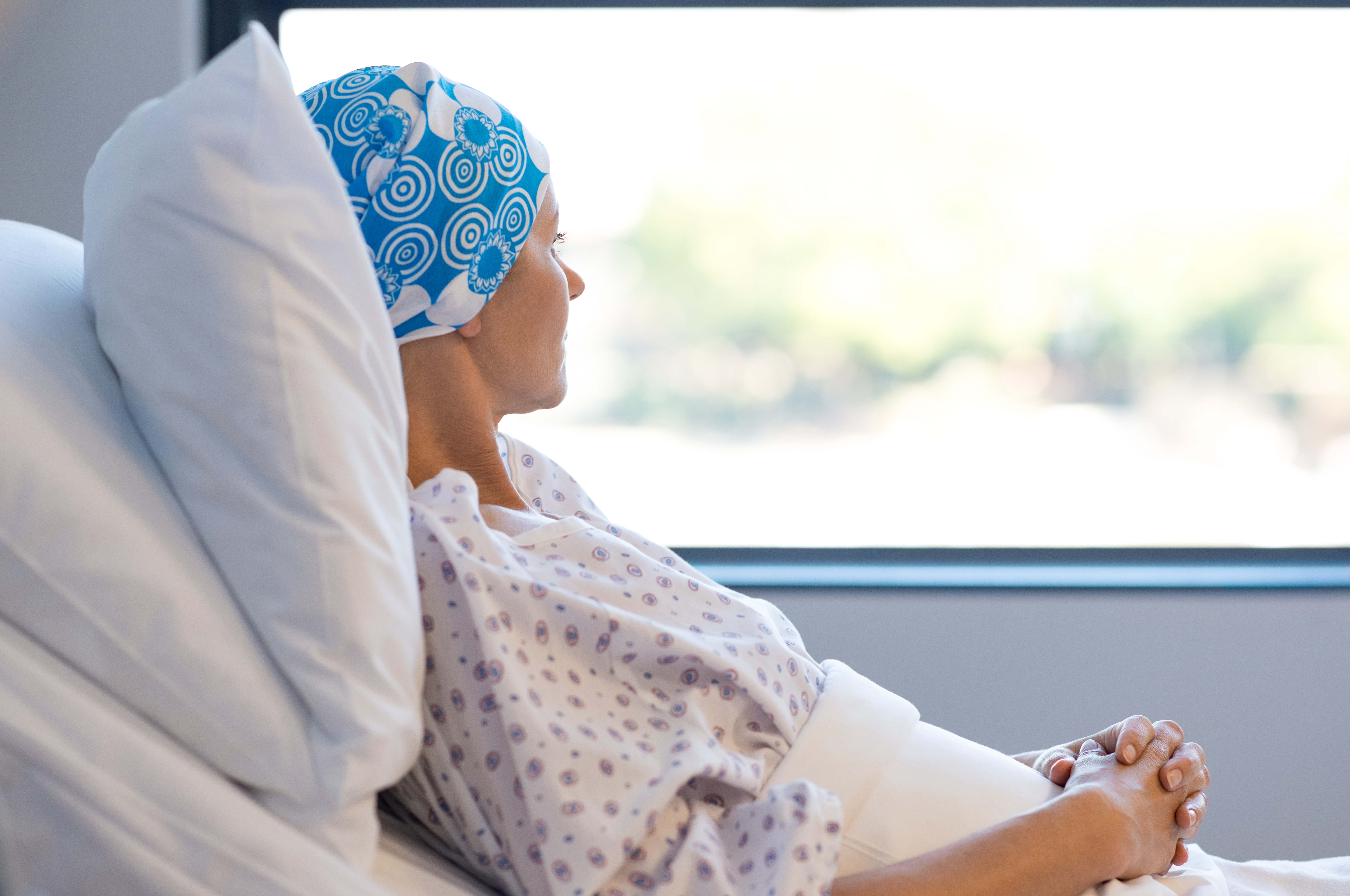 Woman wearing a bandana around her head lying in a hospital bed | Source: Shutterstock