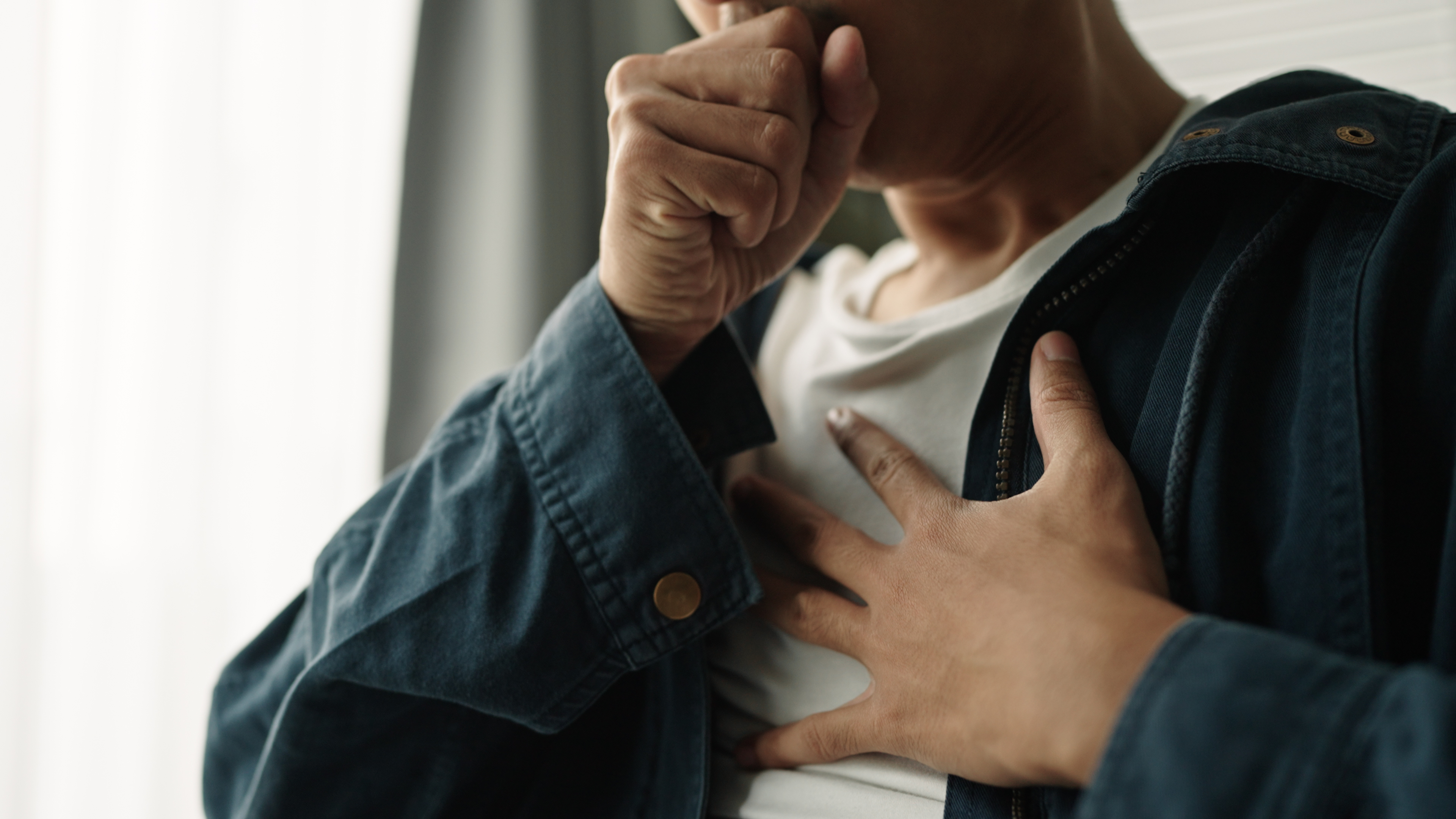 Young man touching his chest, appearing to be in discomfort or pain | Source: Getty Images