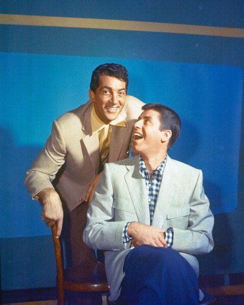 US actor and singer Dean Martin with US actor and comedian Jerry Lewis sitting on a chair in a studio portrait in 1950. | Photo: Getty Images