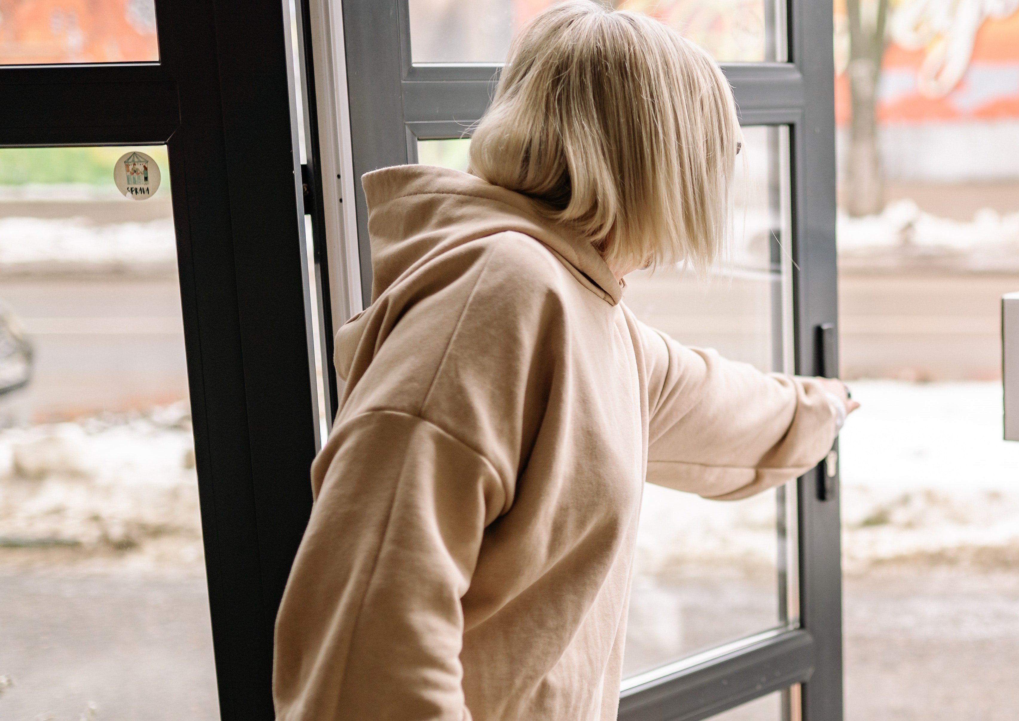 Mujer abre una puerta vidriada. | Foto: Pexels