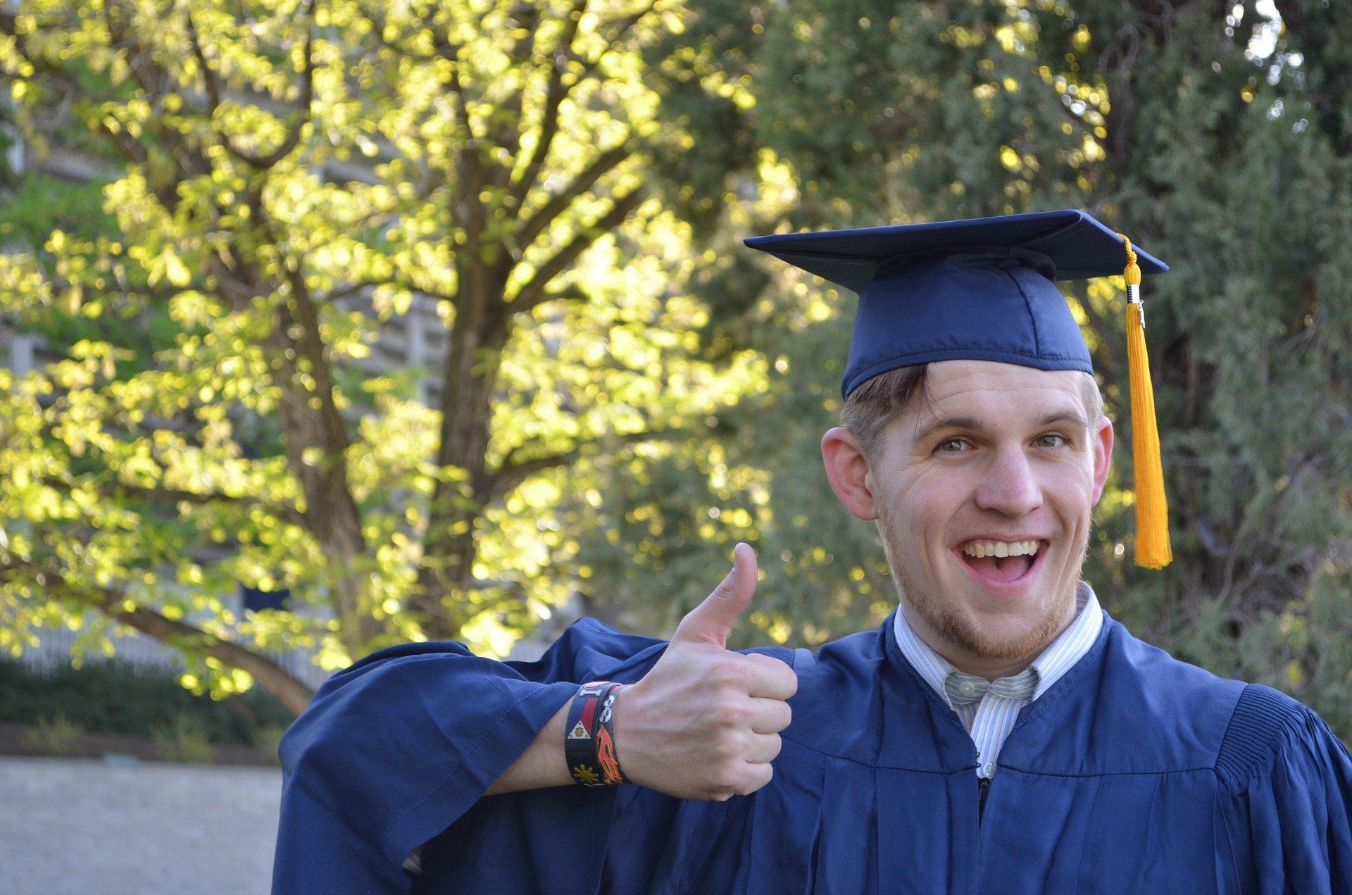 Un hombre muestra un pulgar hacia arriba vistiendo su atuendo de graduación y radiante de orgullo |  Fuente: Pixabay