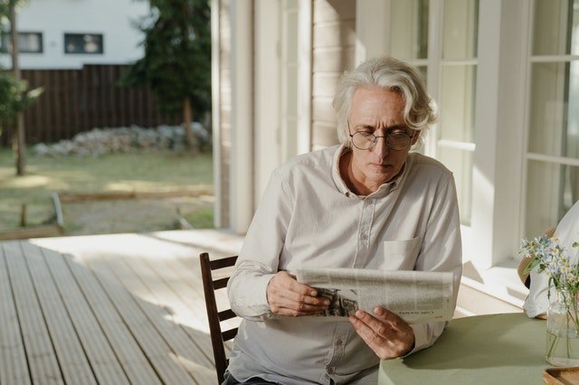 Elderly man reading newspaper on porch | Source: Pexels