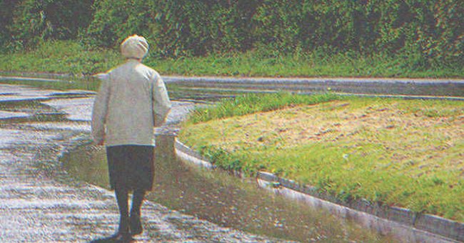Una anciana caminando por una carretera solitaria bajo la lluvia. | Foto: Shutterstock