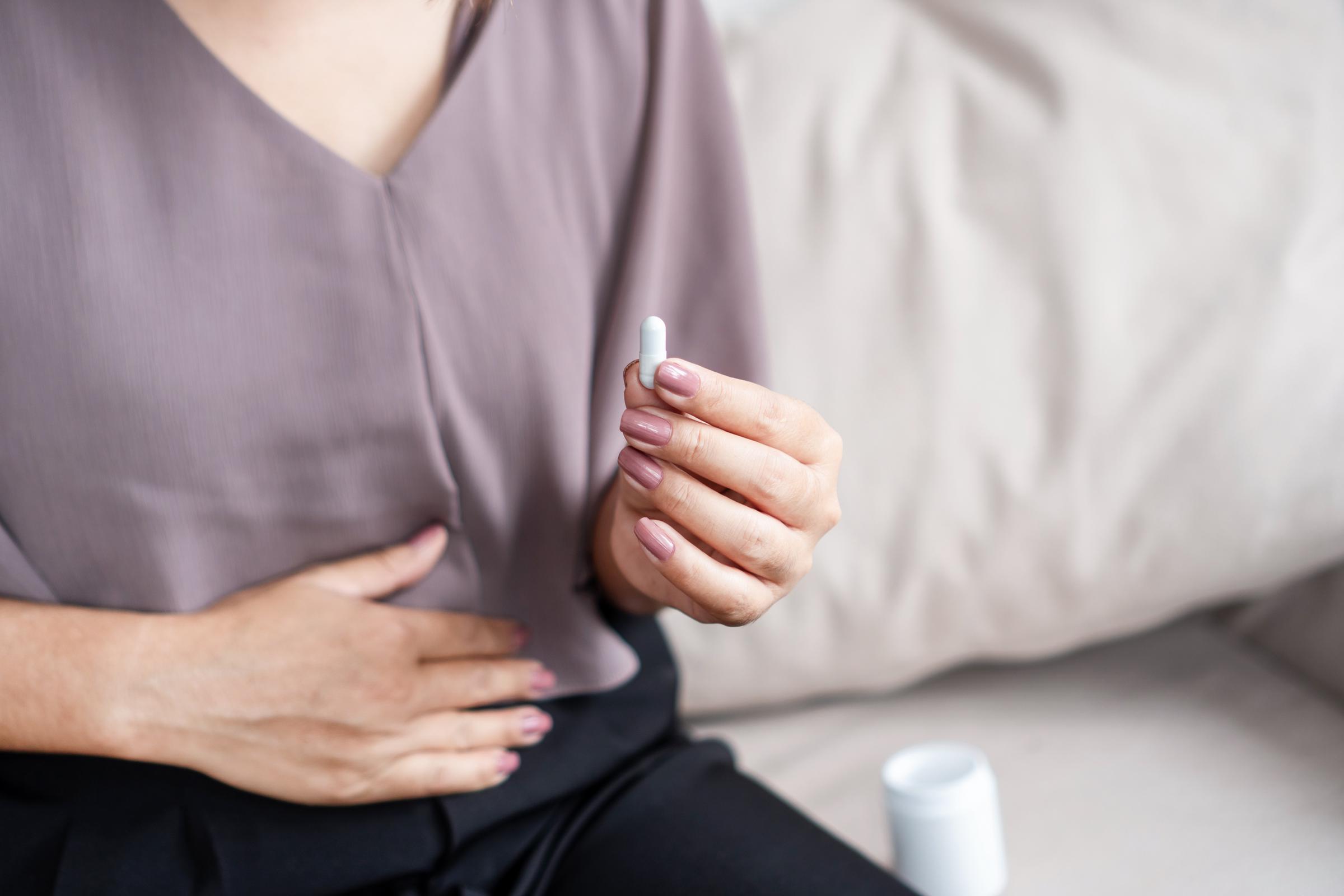 A woman takes a pill to relieve her digestive condition | Source: Getty Images