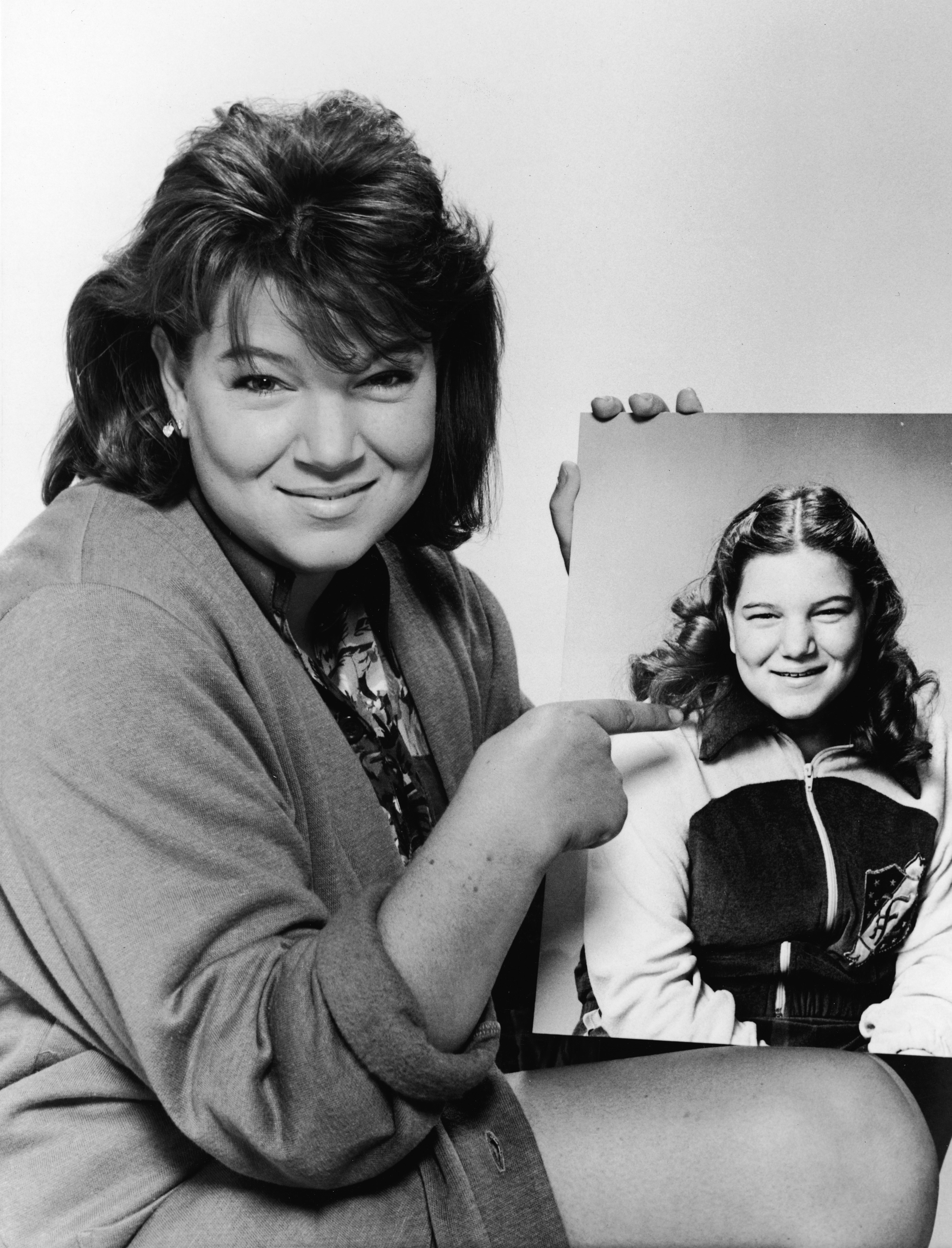 Mindy Cohn pointing to a publicity picture of herself from 1979, dated 1985 | Source: Getty Images