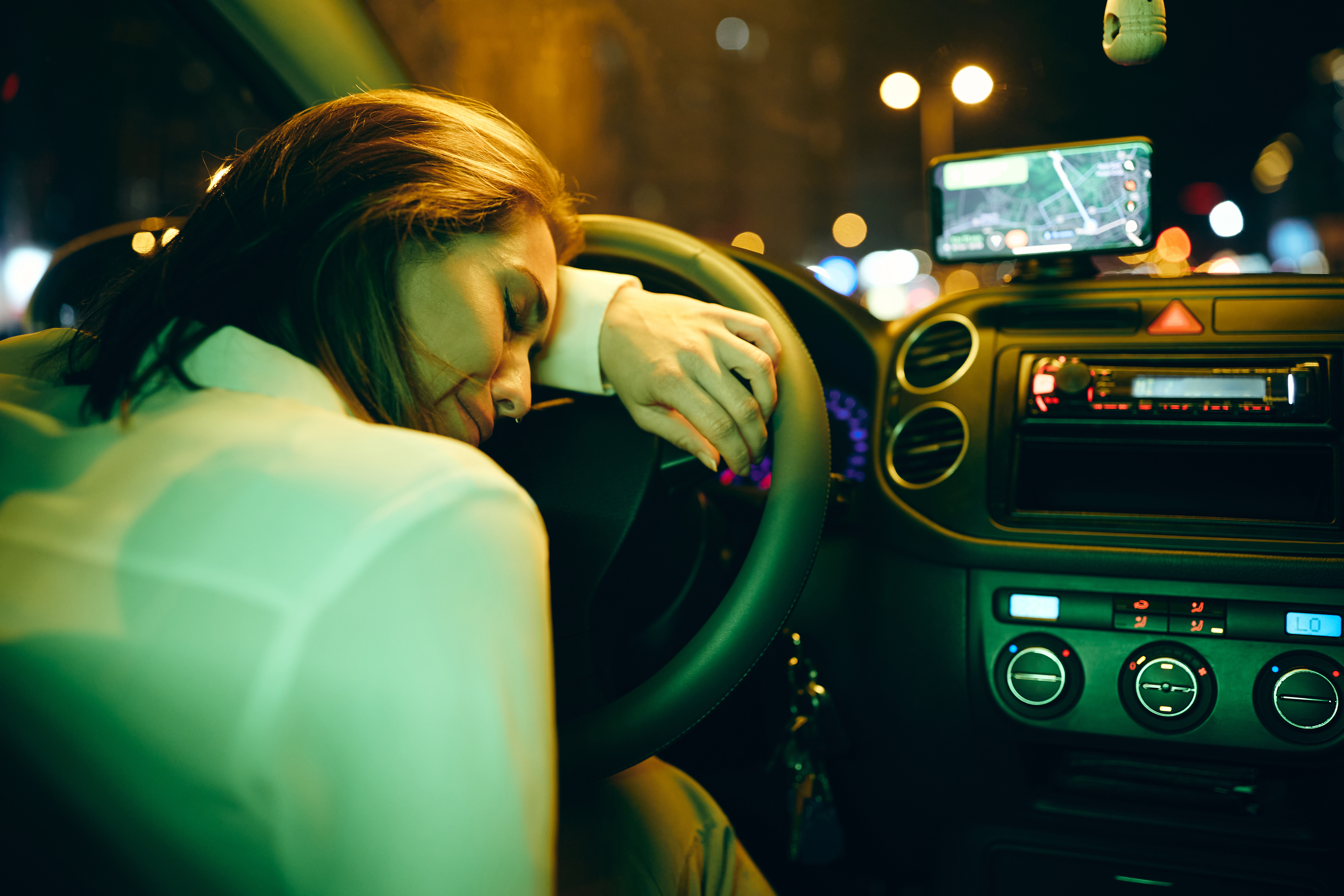 Young depressed woman leaning on steering wheel and crying in car at night. | Source: Shutterstock