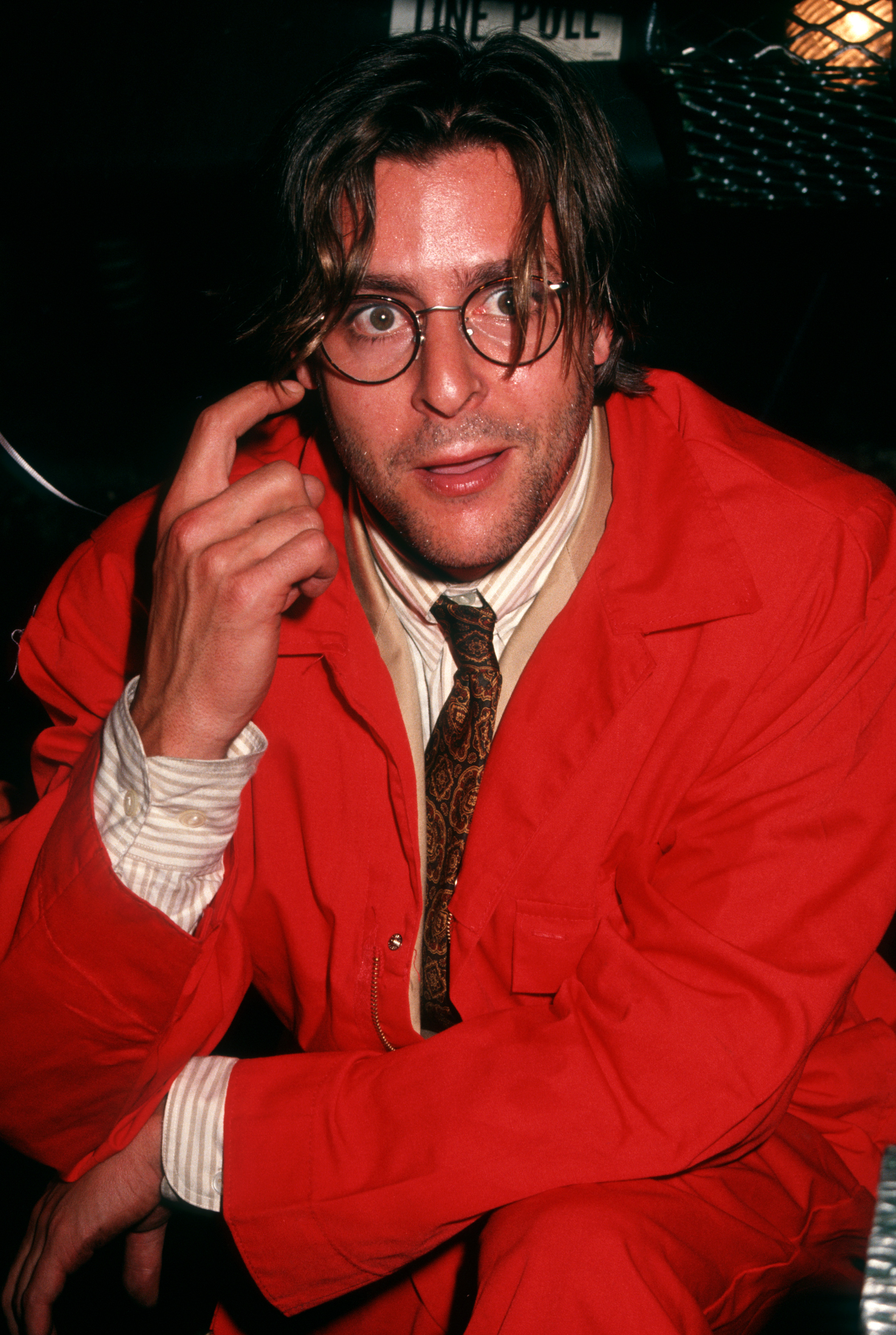 Striking a playful pose in a vibrant red jumpsuit paired with round-framed glasses and a patterned tie, the actor celebrated the premiere party for "The Dark Backward" at The Gas Station in New York City. | Source: Getty Images