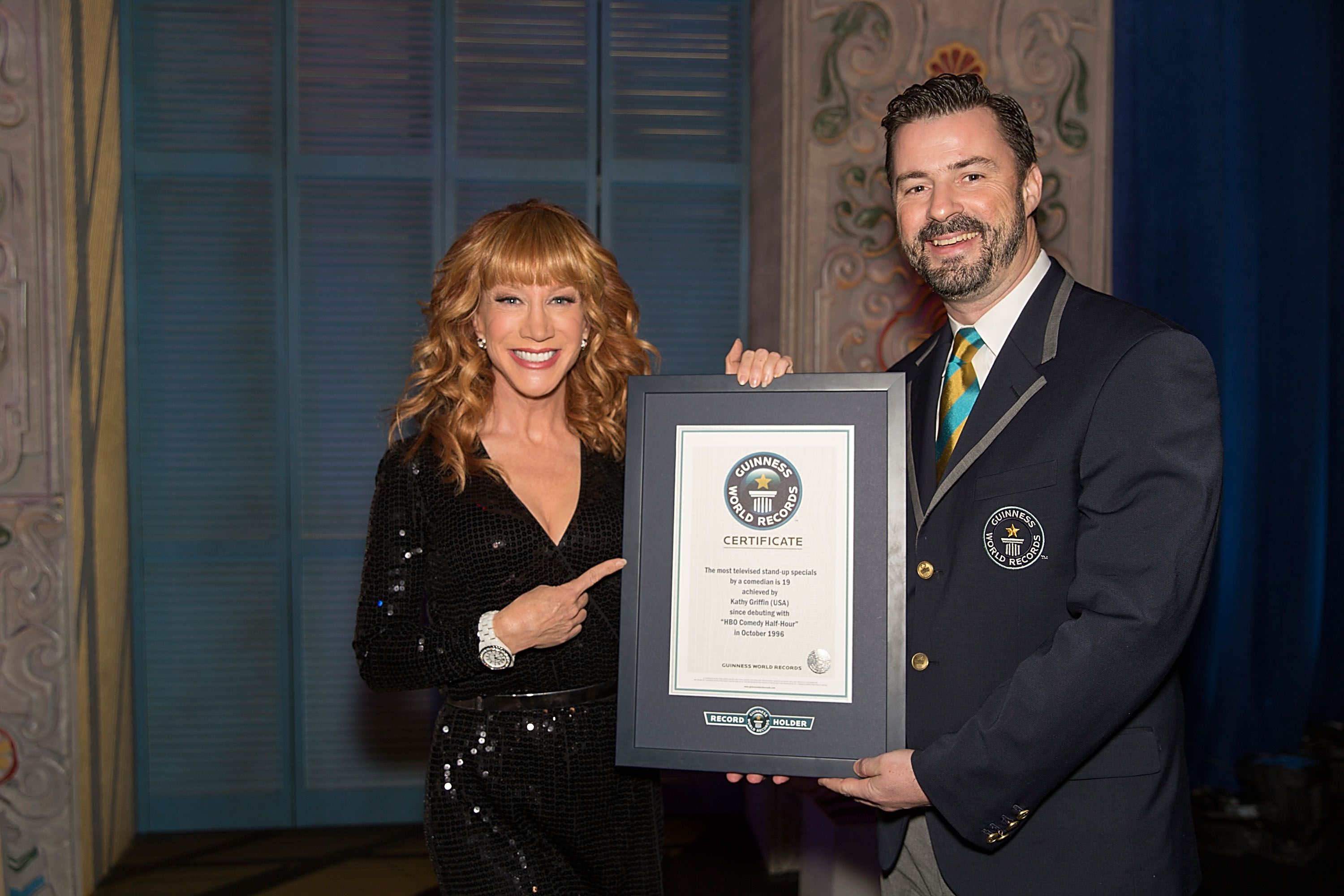 Kathy Griffin with a Guinness World Record representative after breaking the Guinness World Record for the most stand-up comedy specials by a comedian on November 24, 2013. | Source: Getty Images