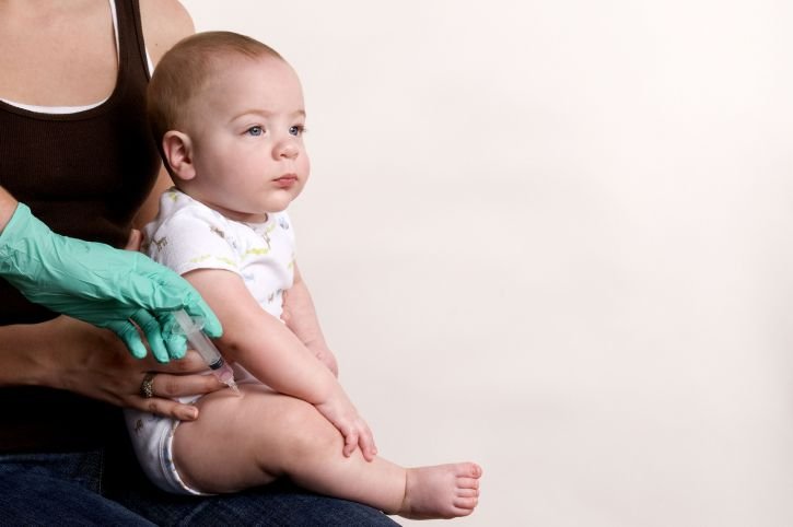 La mère tient son enfant dans ses bras pendant que le médecin le vaccine. | Image : Pixnium