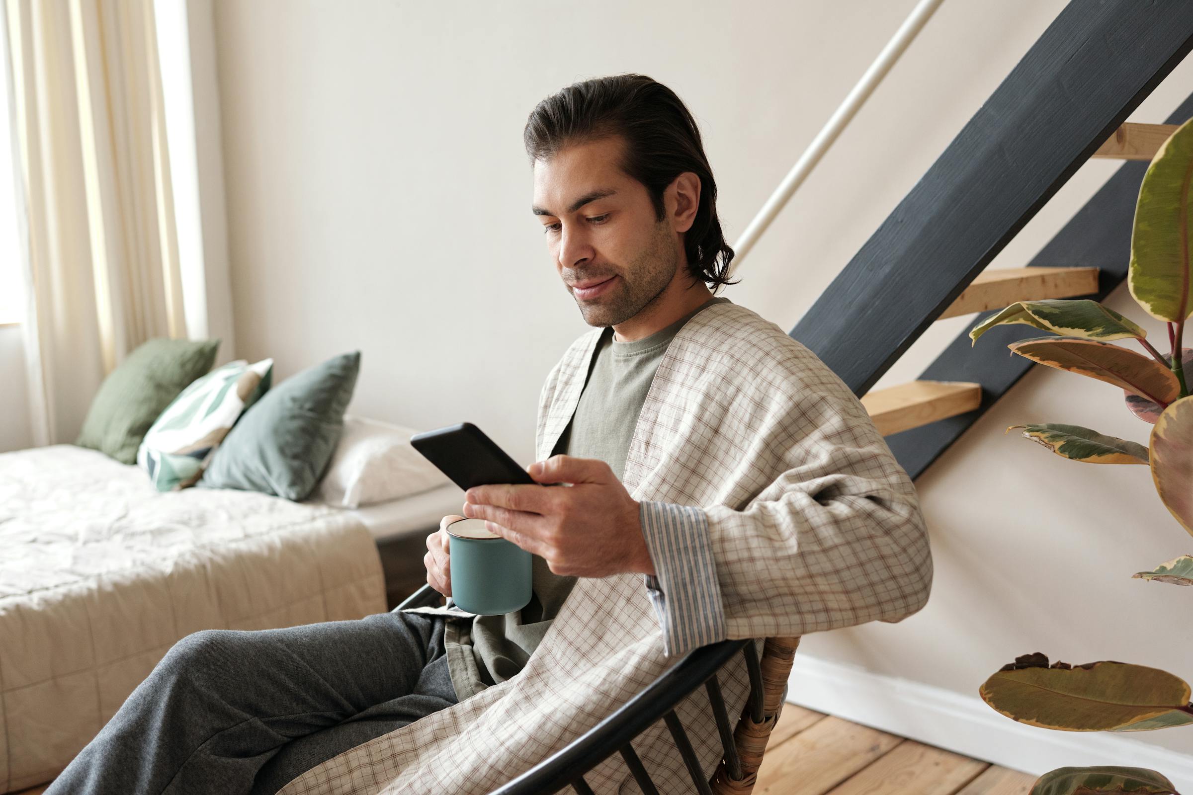 Man looking at his phone while drinking coffee | Source: Pexels