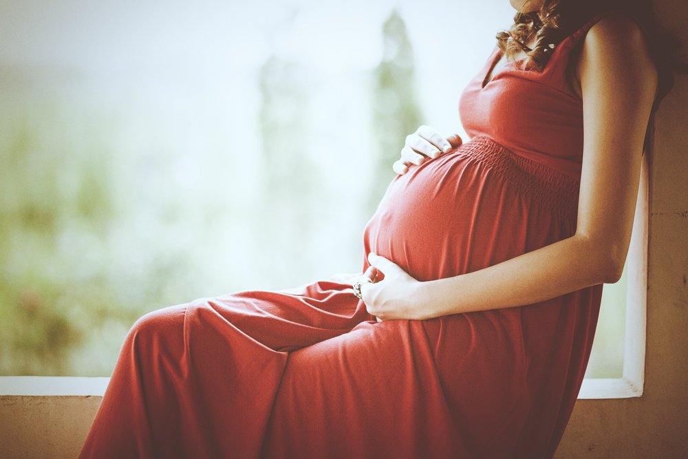 Imagen de una mujer embarazada tocándose la panza con las manos. | Fuente: Shutterstock