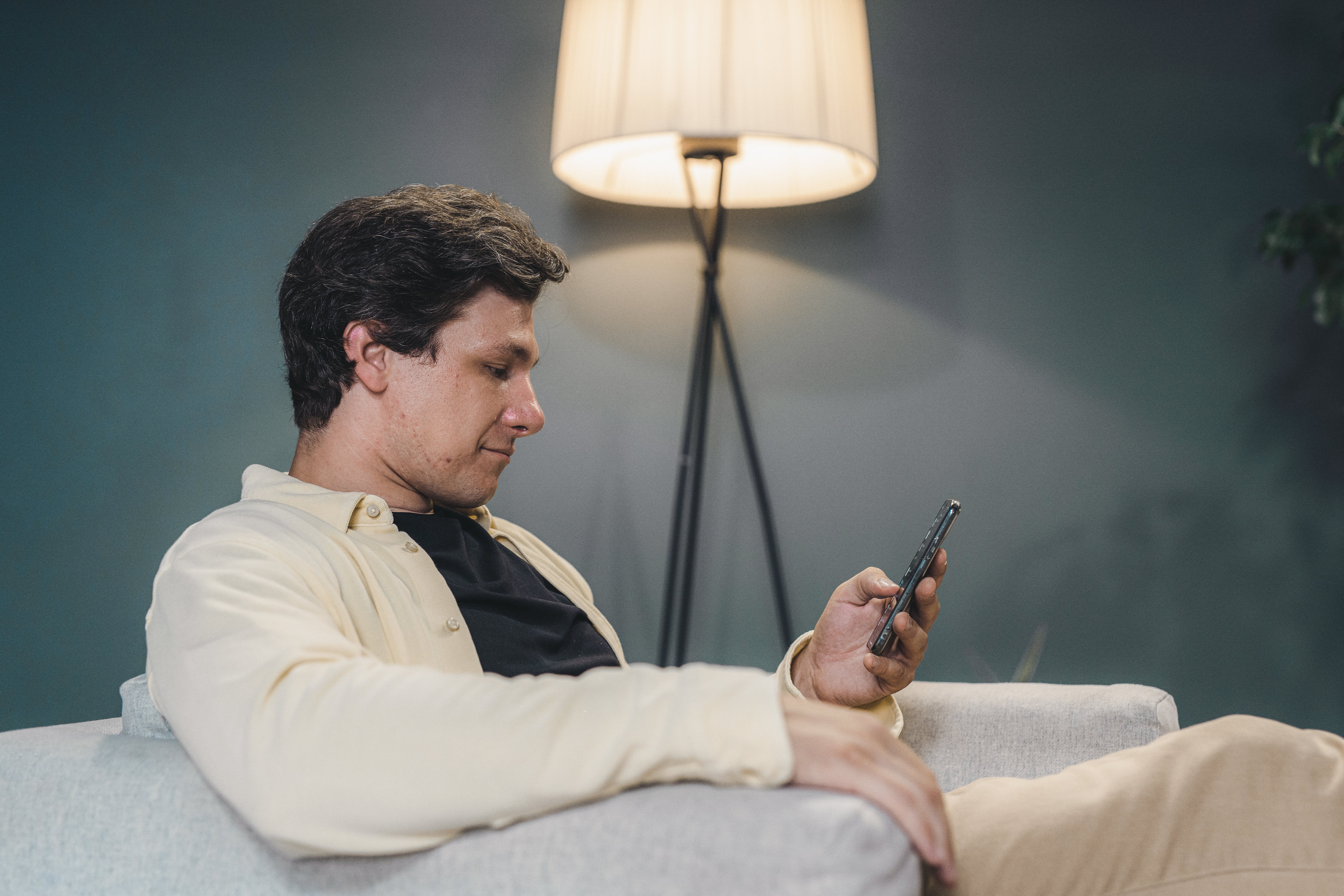 A man sitting on a sofa using a smartphone | Source: Pexels