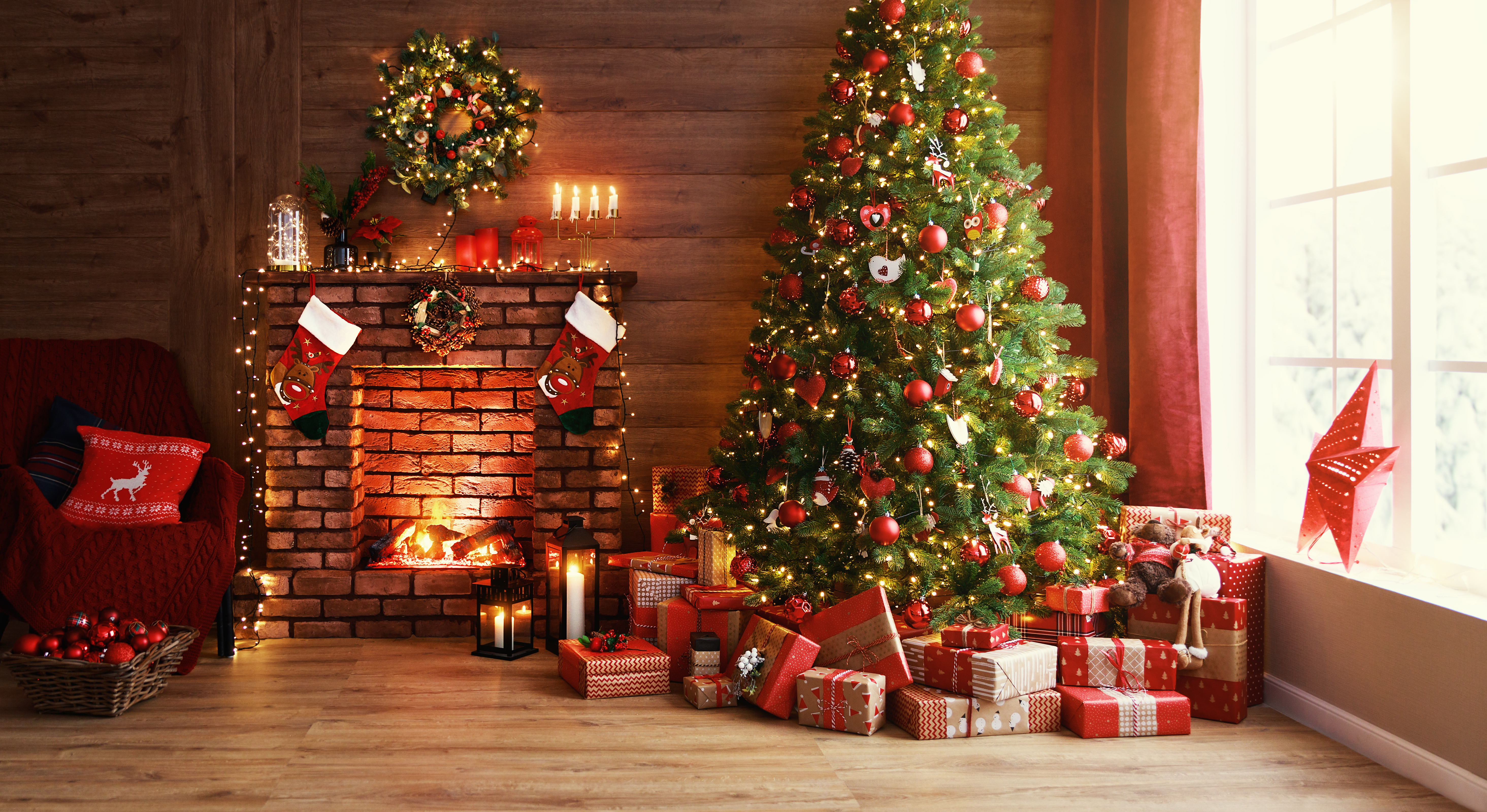 A Christmas tree placed next to a fireplace with gifts and decorations | Source: Shutterstock