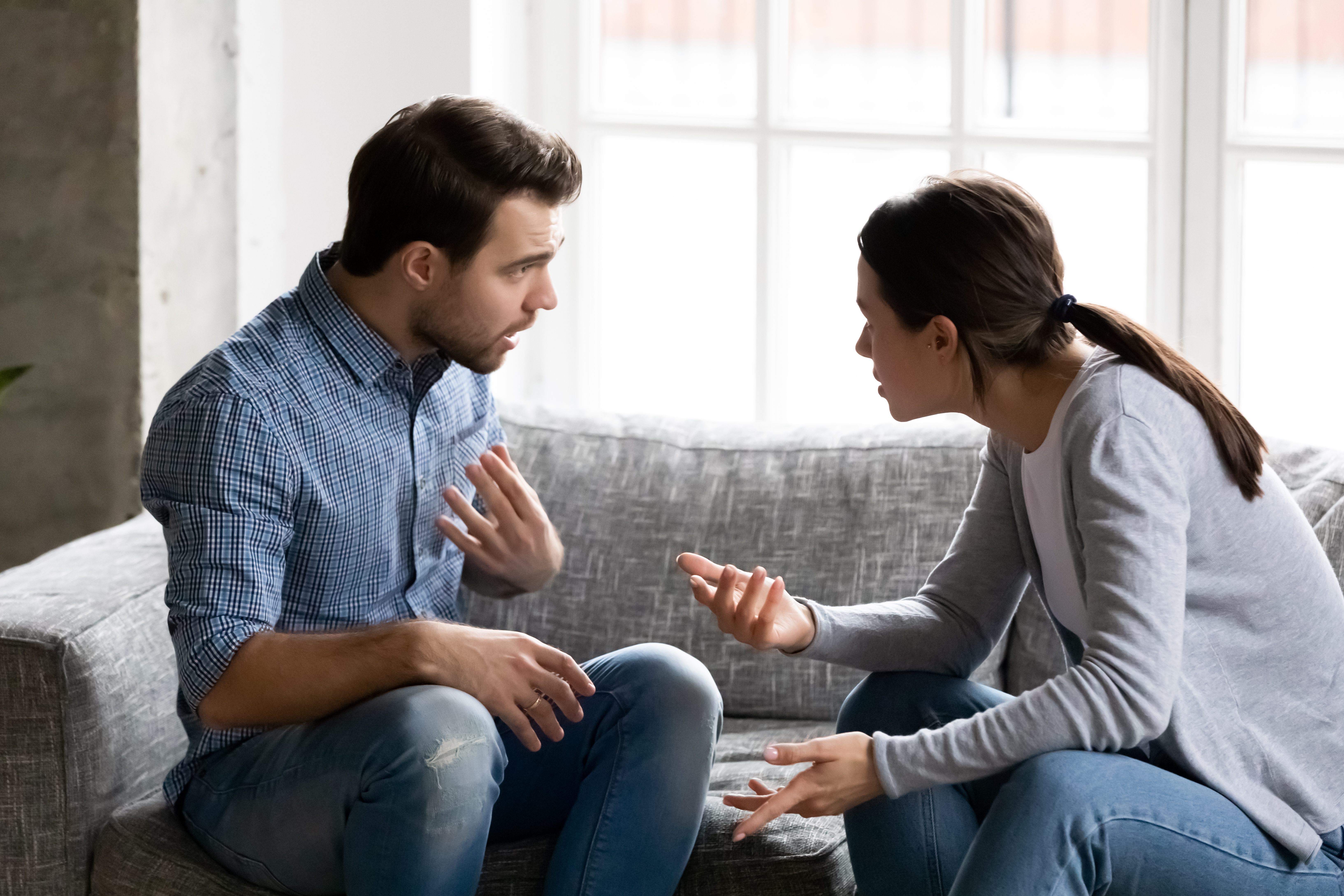 A married couple arguing while sitting on the sofa | Source: Shutterstock
