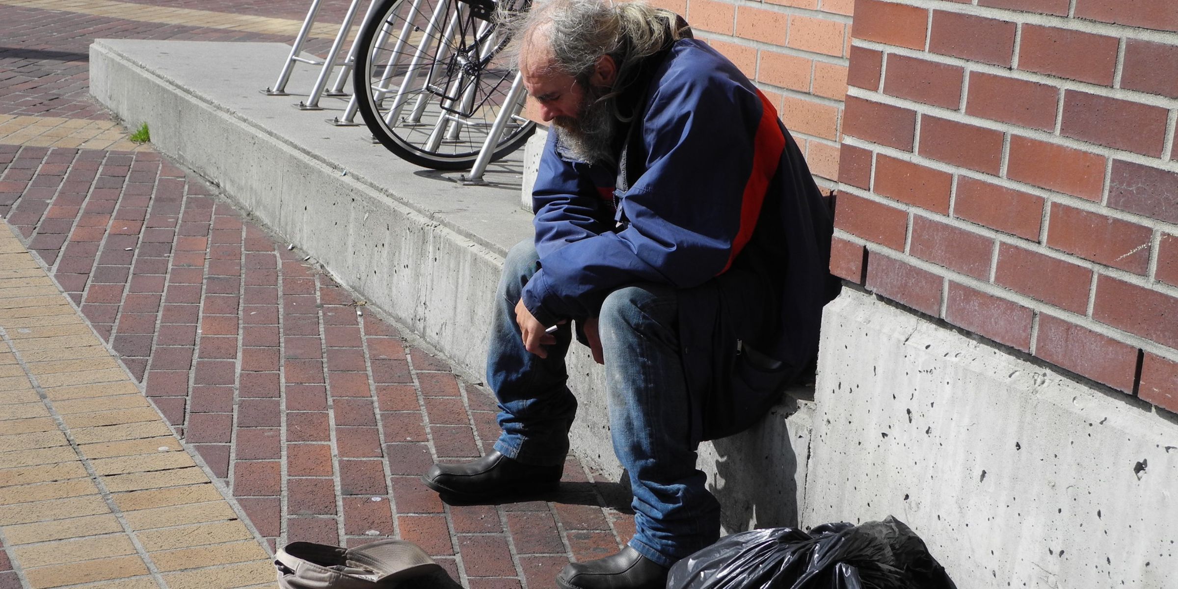 A poor elderly man sitting on the pavement | Source: Flickr